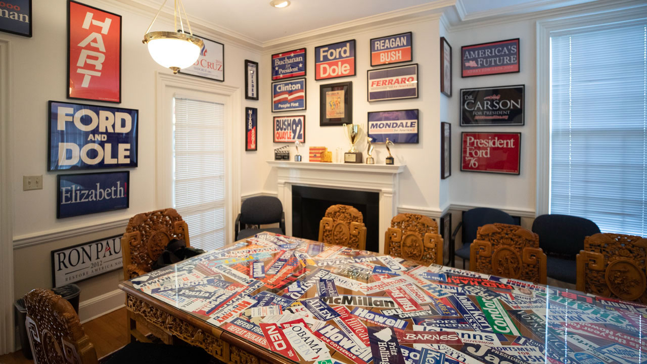 Table covered with political bumper stickers and political signs on the wall