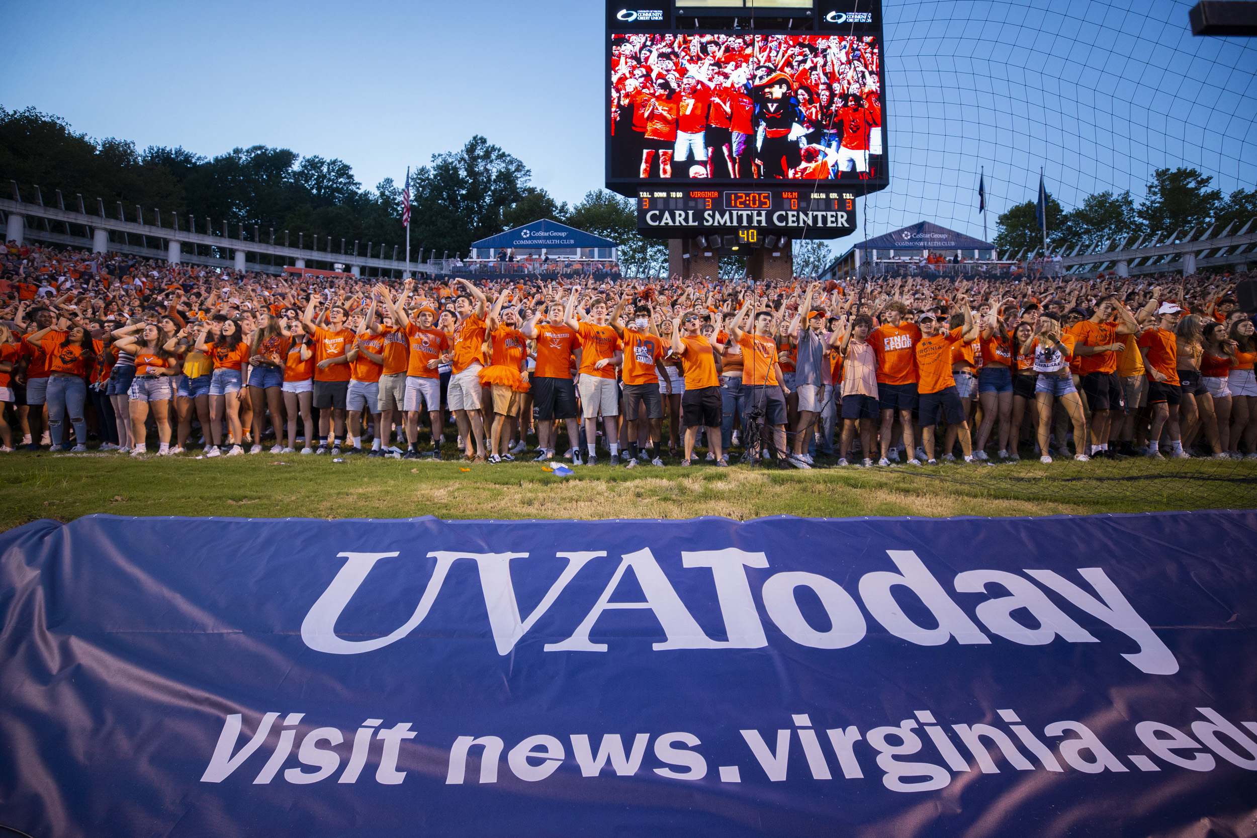 Crowd on the Scott Stadium field for a photo with the sign UVA  TODAY visit news.virginia.edu in front of them