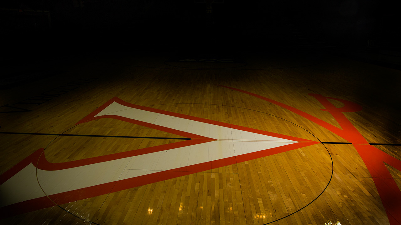 Virginia V on a hardwood basketball floor with only the V in the light
