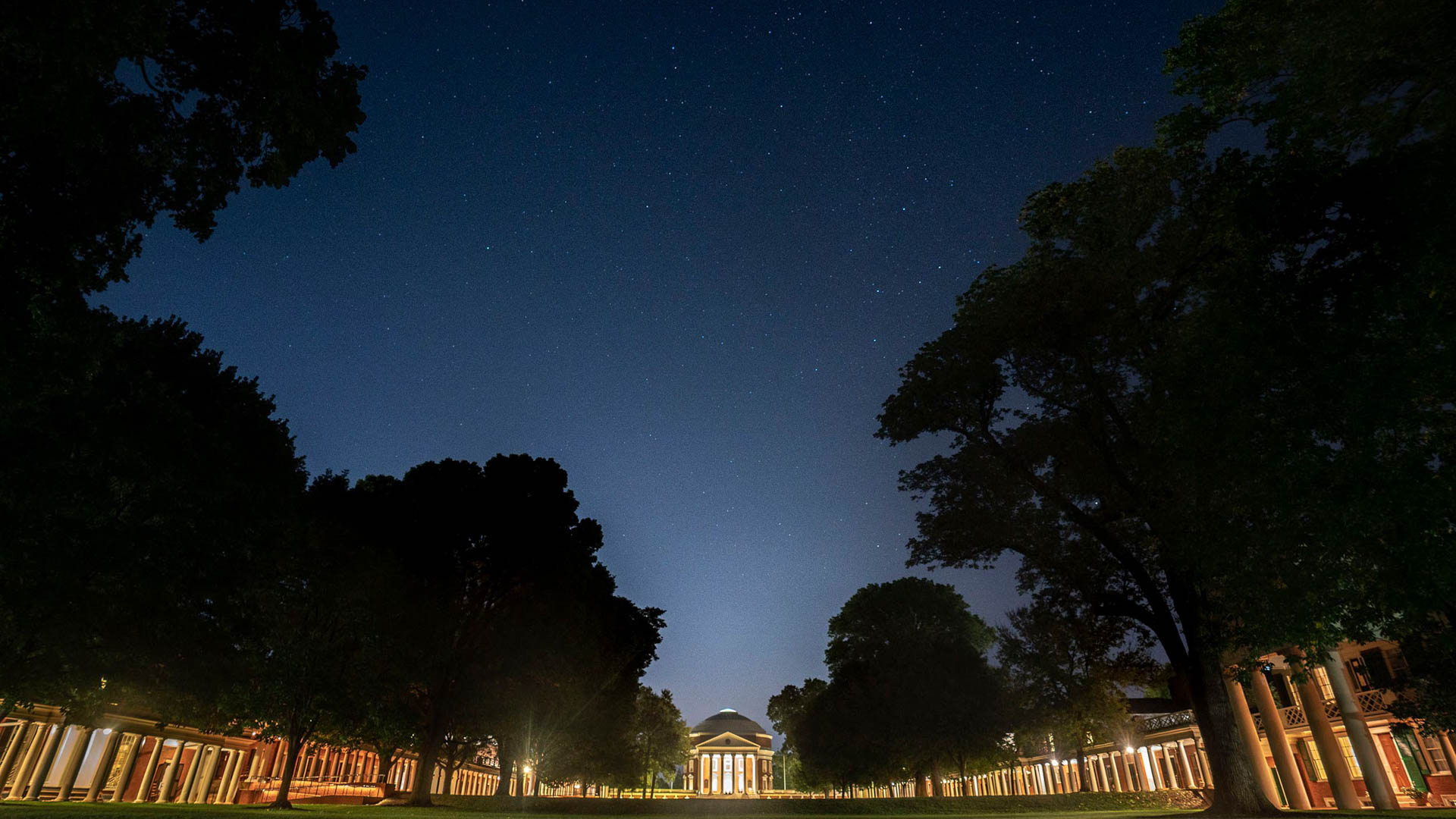 Rotunda and the Lawn buildings lit up by lights at dusk