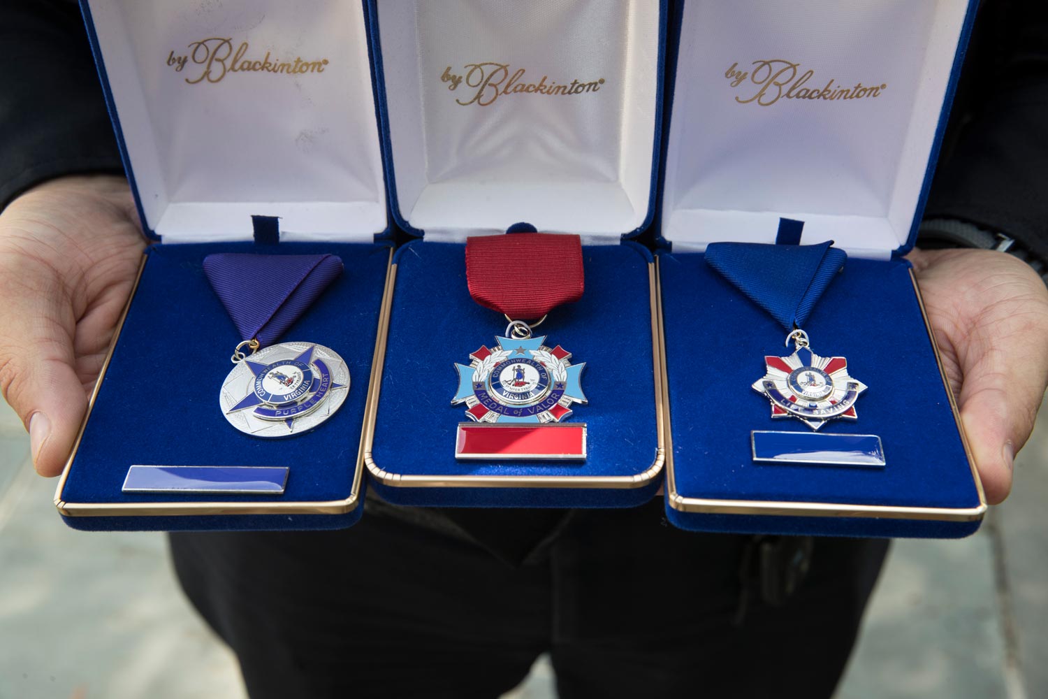 Officer Champigny holds his Purple Heart, Medal of Valor and Life Saving Award in their cases