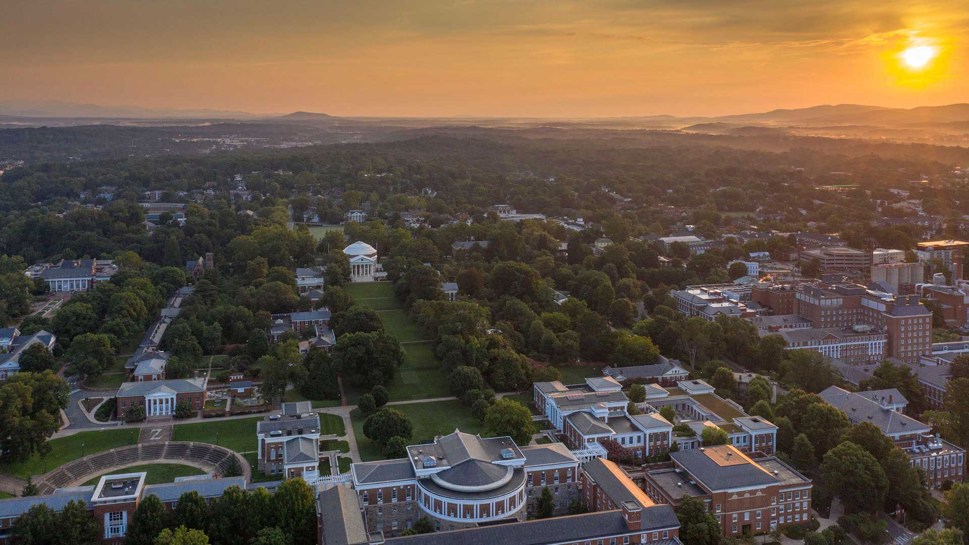 Arial View of the Rotunda and lawn from Cabell hall as the sun creates a yellow and orange sunset