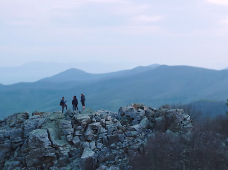 people stand on rocks at the top of a mountain