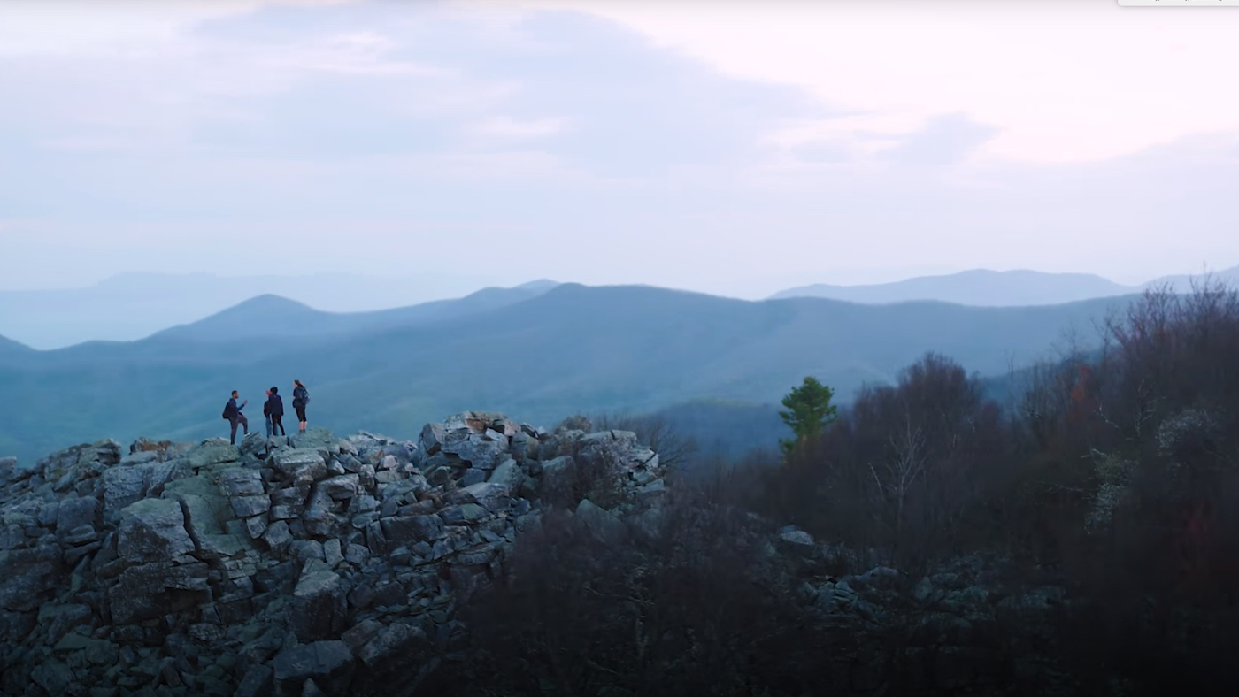 people stand on rocks at the top of a mountain