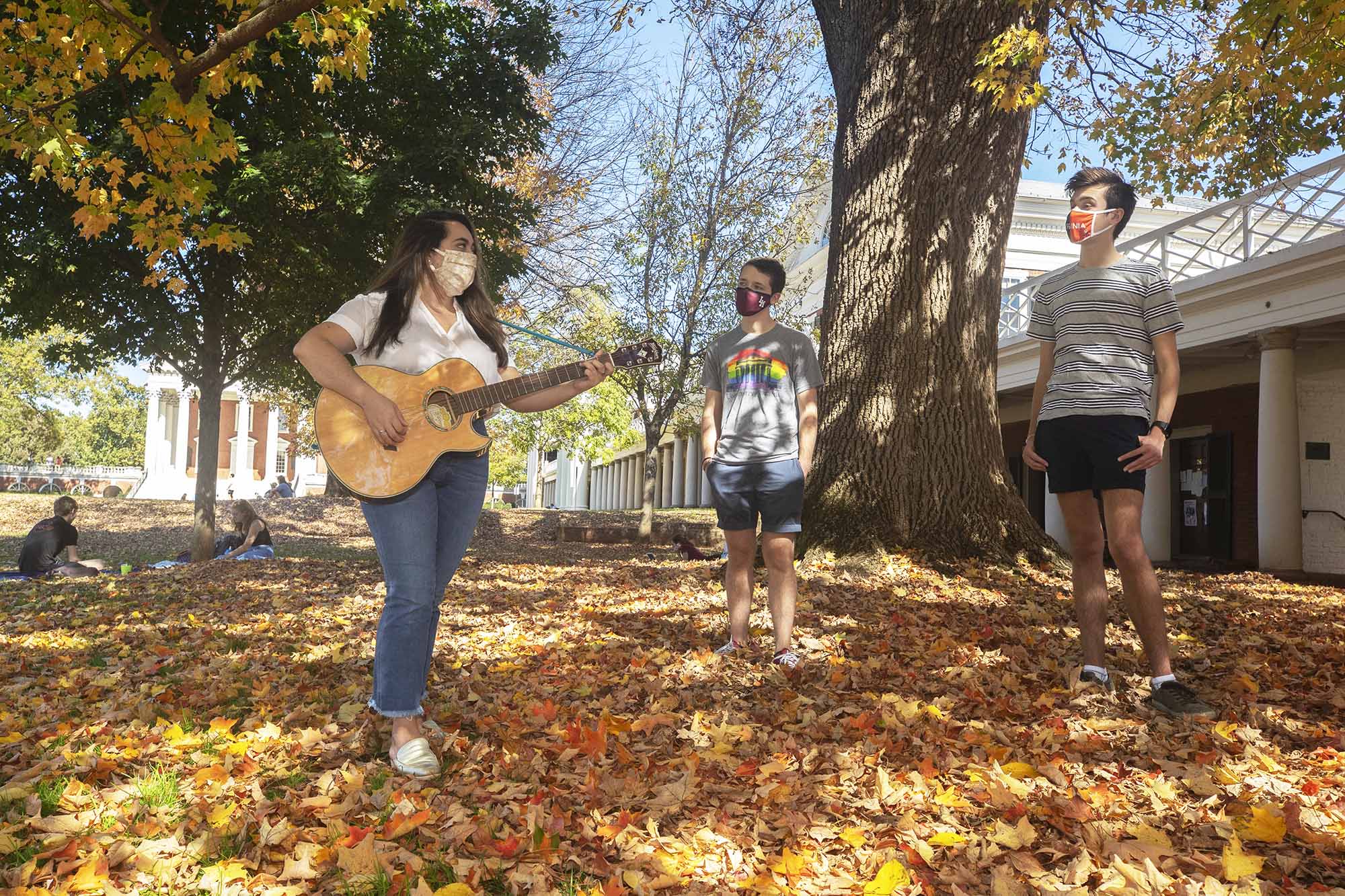 Veronica Merril performs for first-year students Jacob Moore and Lewis Kothmann on the Lawn in the leaves