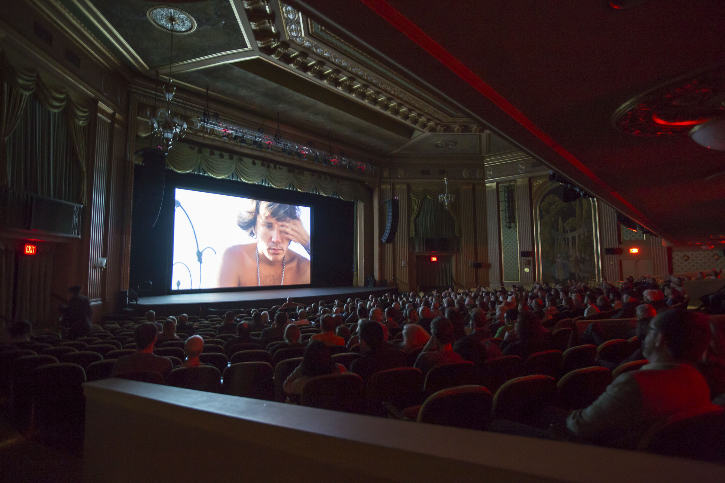 Audience in a theatre watching a movie on the screen