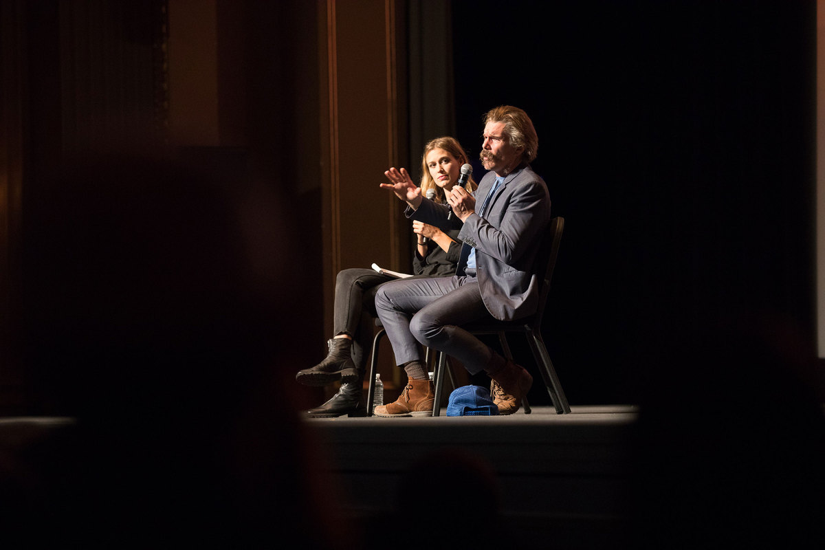 Two people sitting on stage talking to crowd