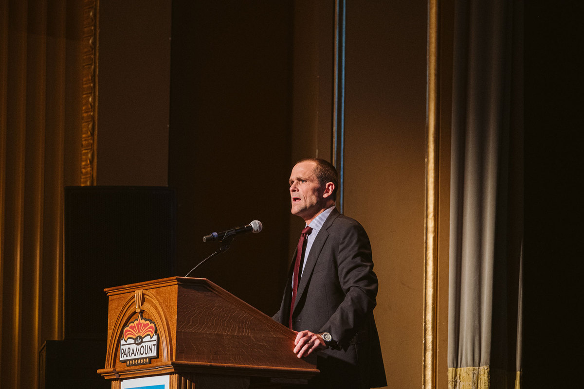 Jim Ryan standing a podium giving a speech