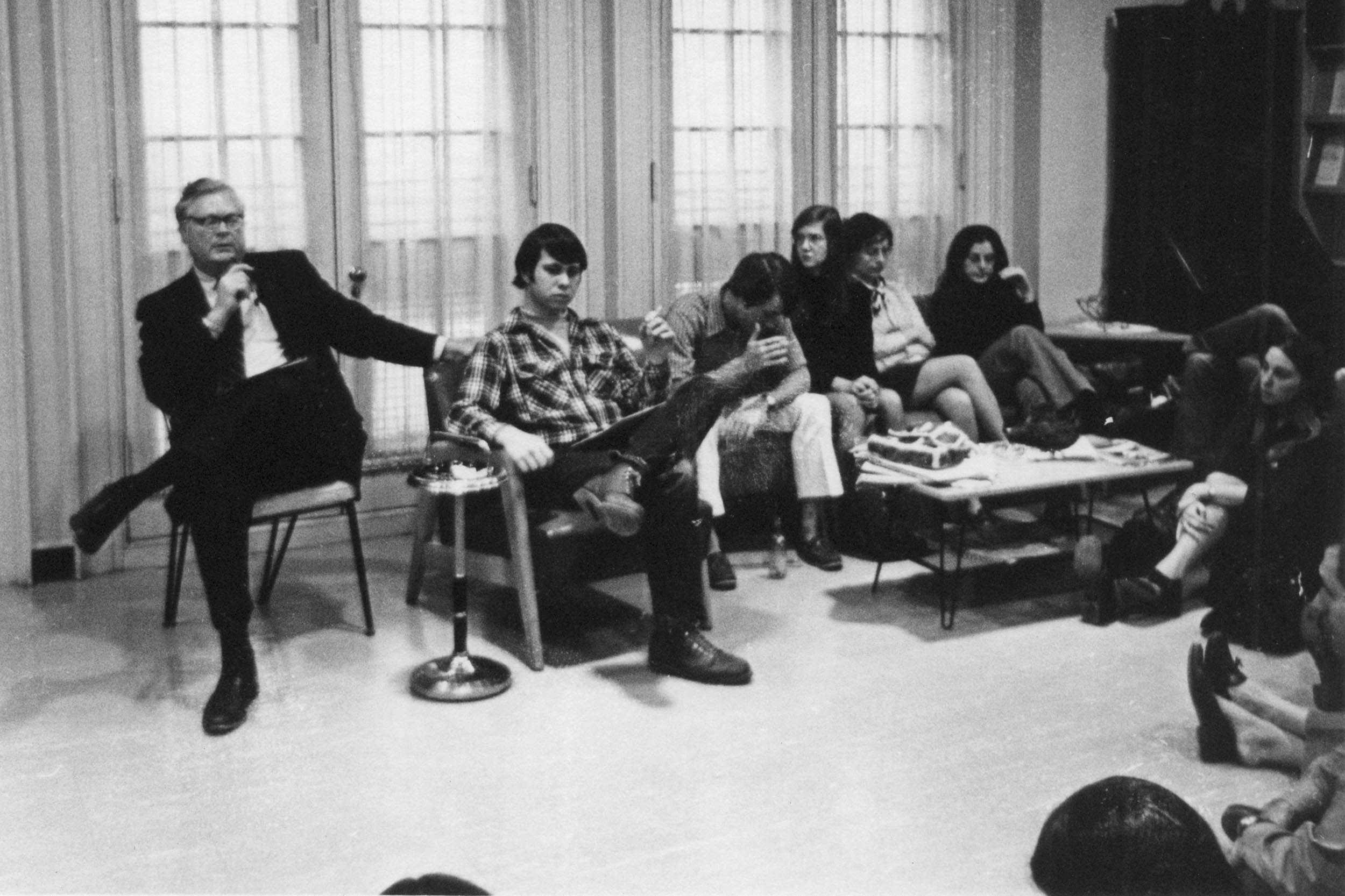 black and white photo of people sitting in a living room