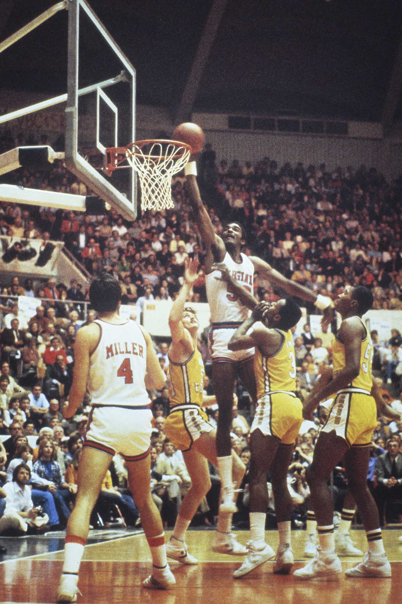 Old image of Ralph Sampson jumping above his opponents to dunk the ball