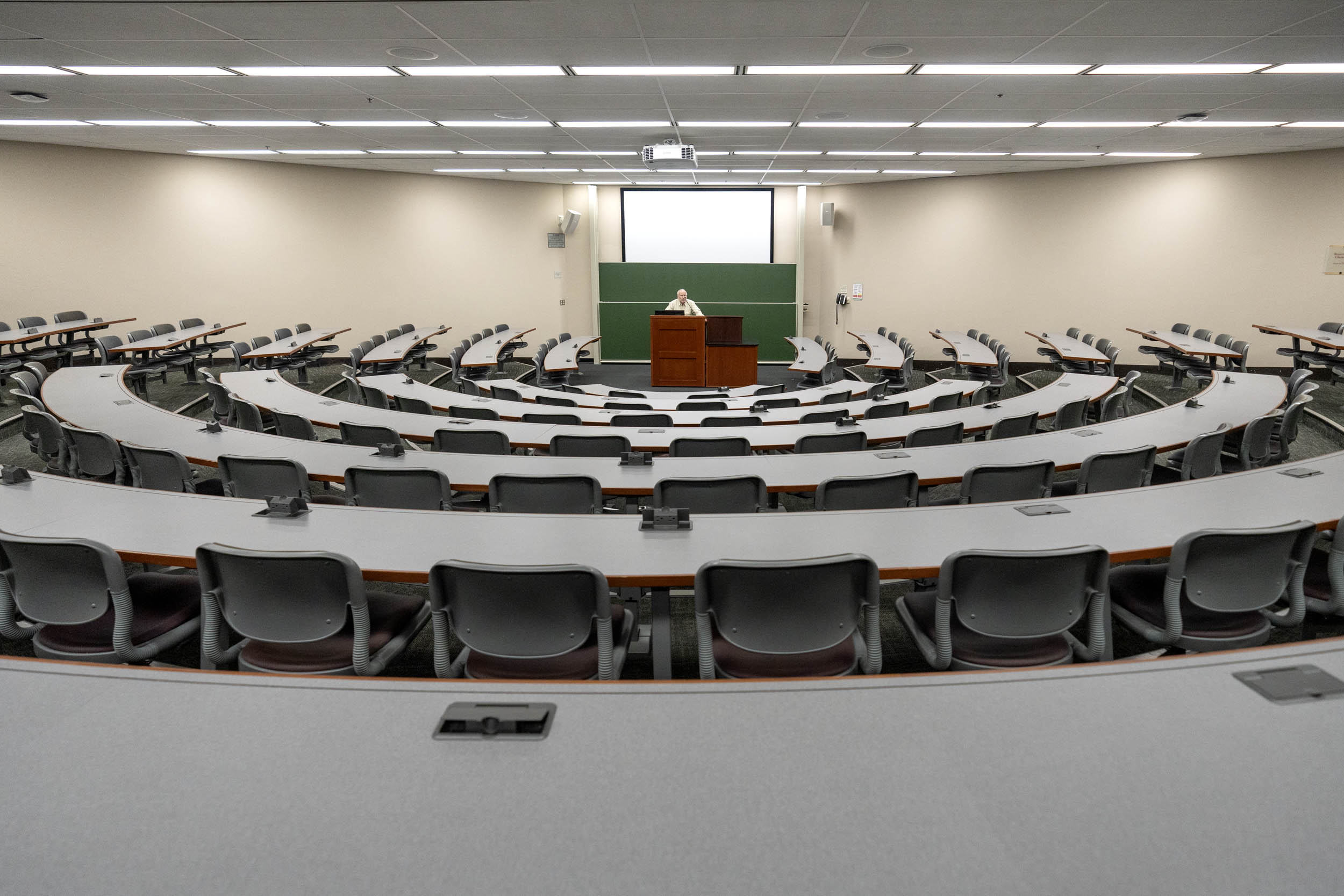 Professor standing at a podium with an empty classroom