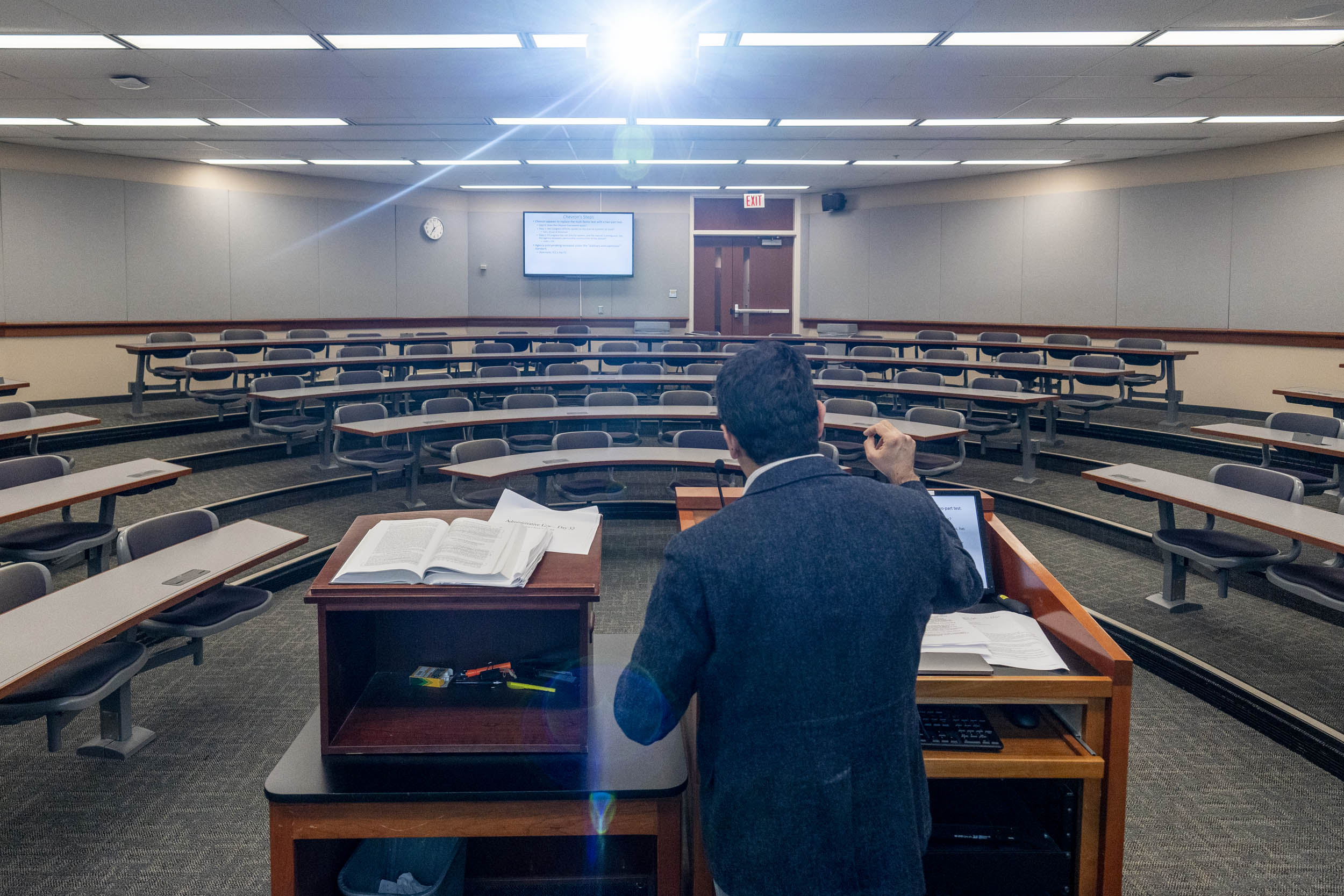 Professor standing at a podium with an empty classroom