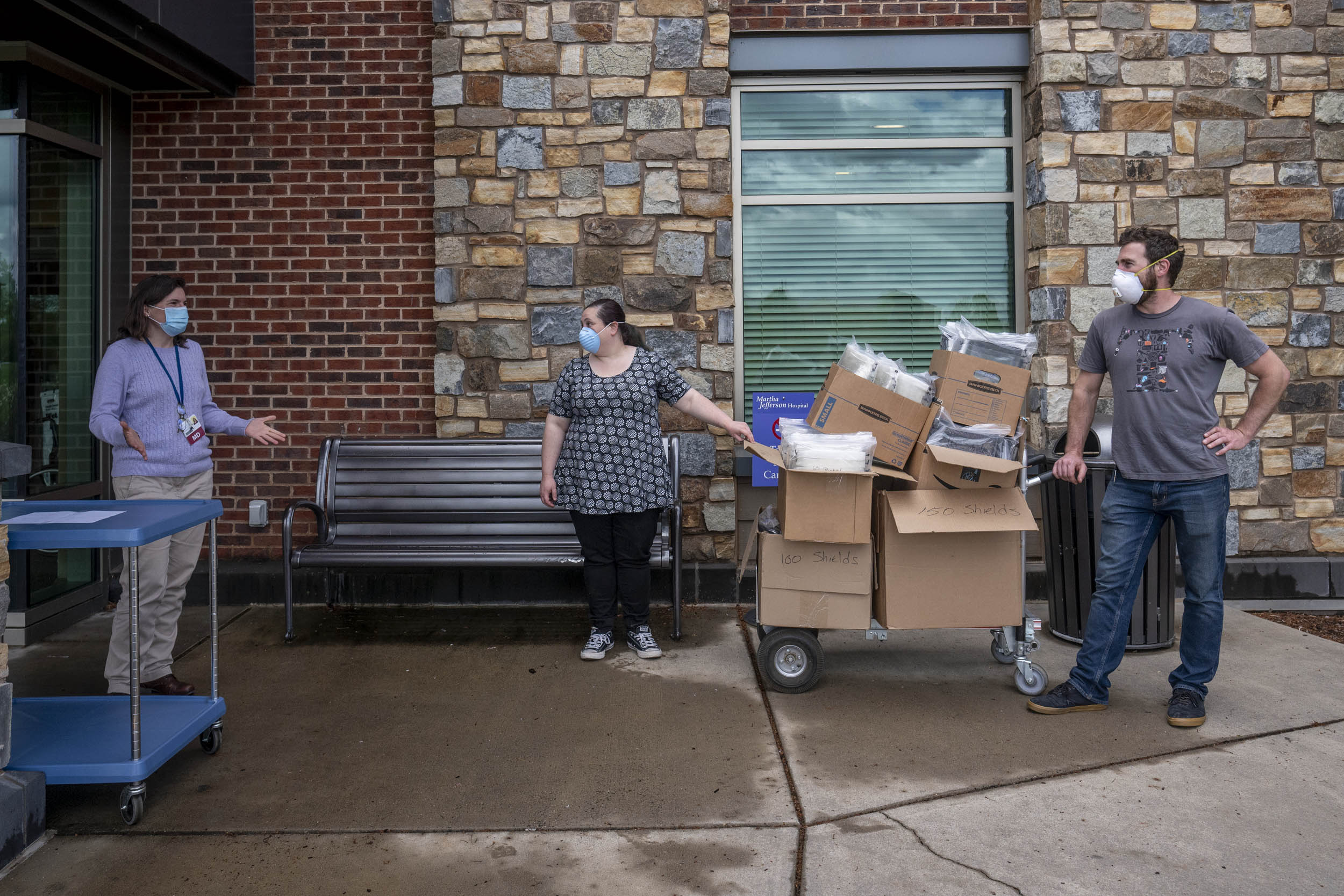 staff members talking while holding a trolly of supplies in brown boxes