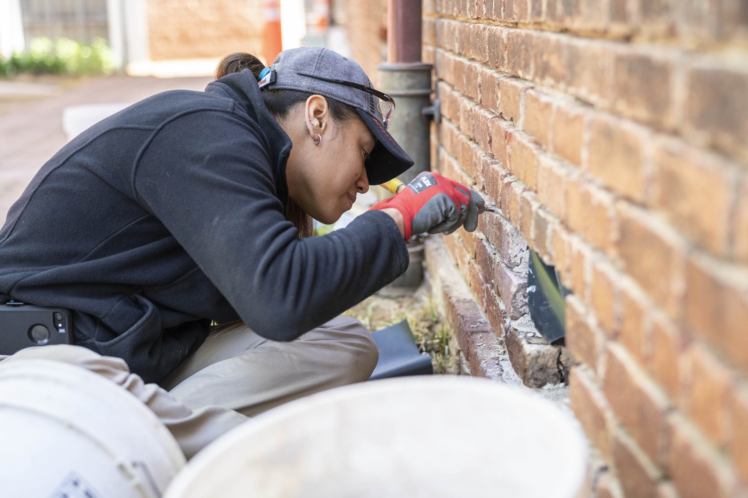 Woman scraping out mortar in the bricks