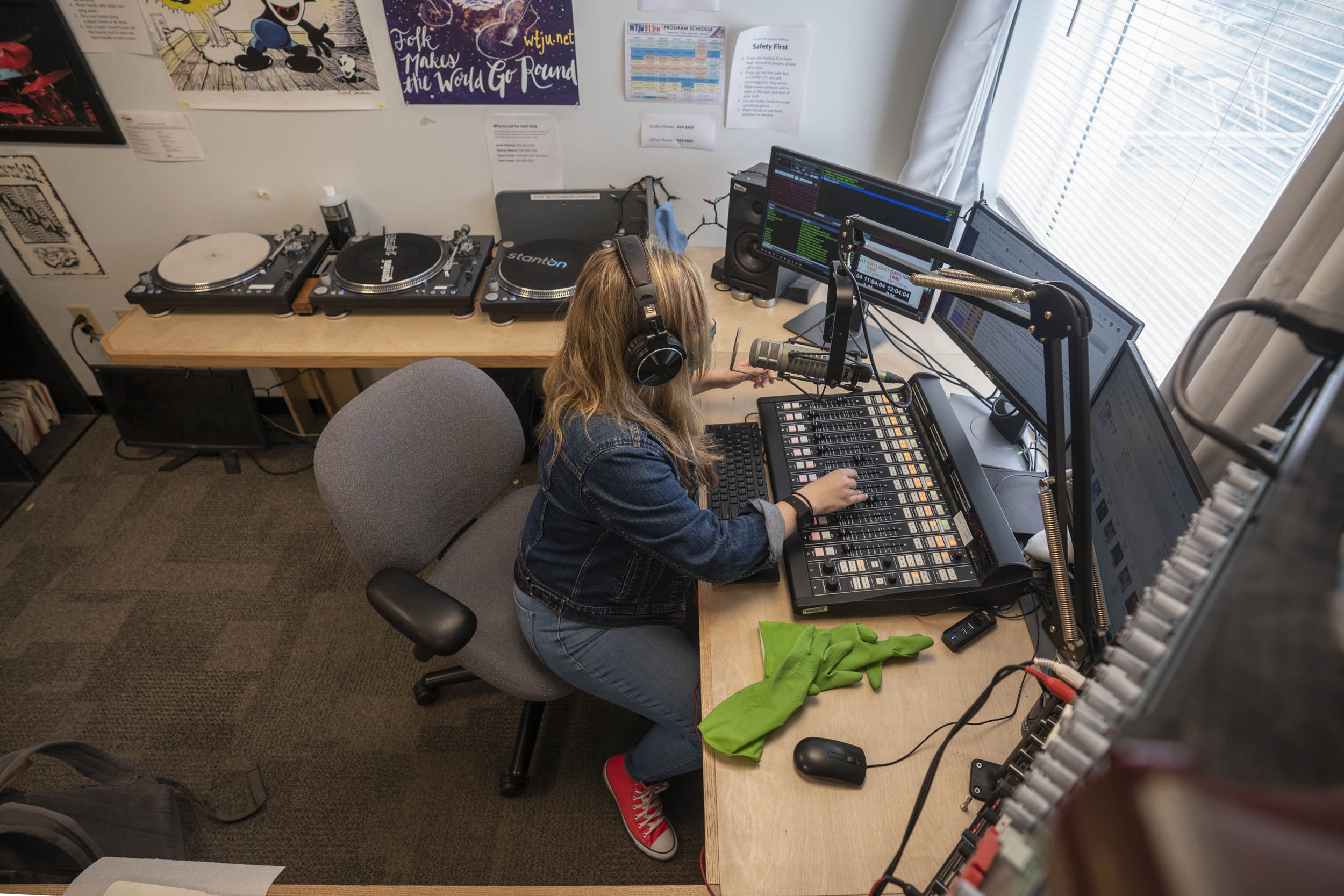 Woman sitting in a chair with headphones on while working a radio soundboard