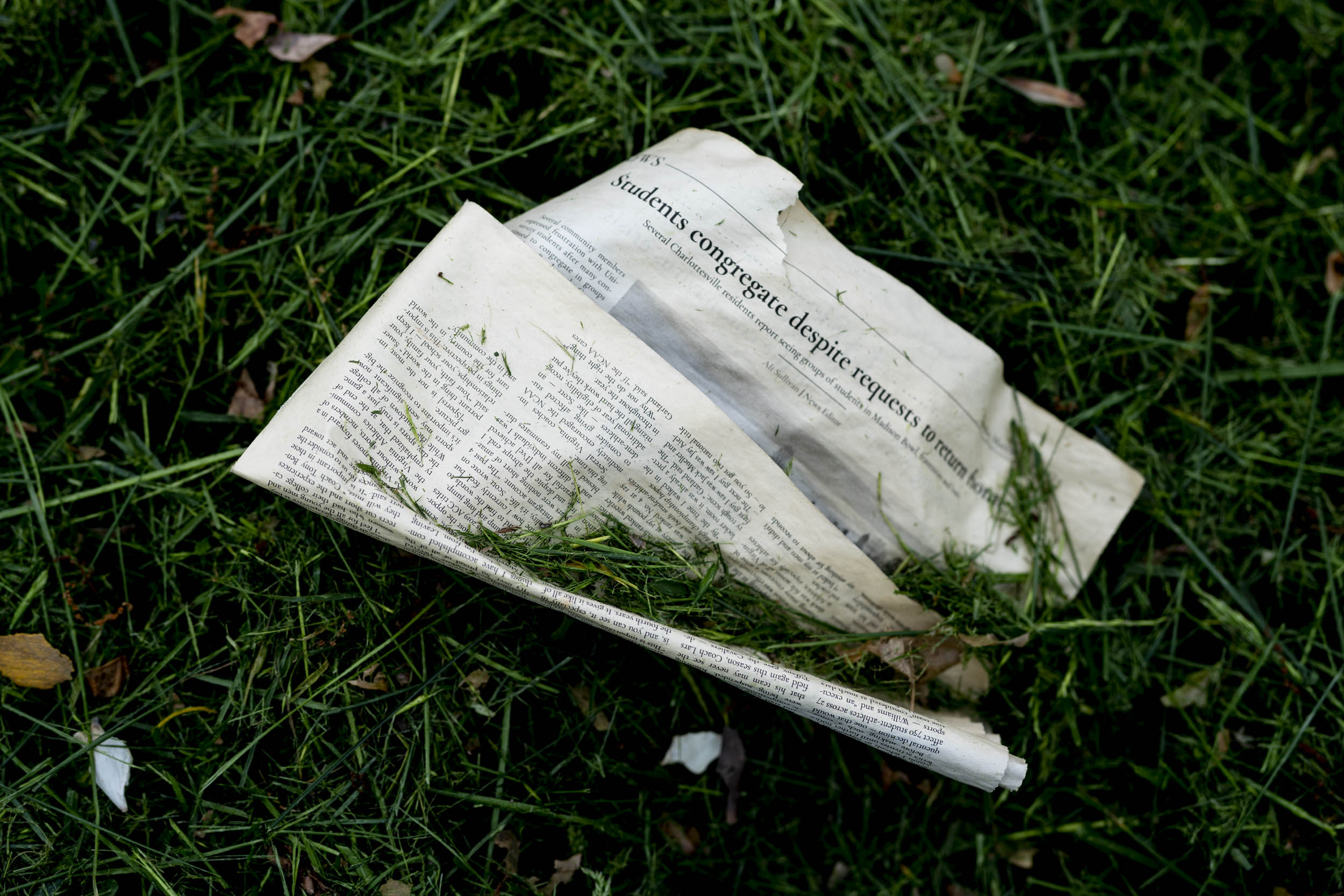 Torn Newspaper folded on the lawn with grass clippings on top of it