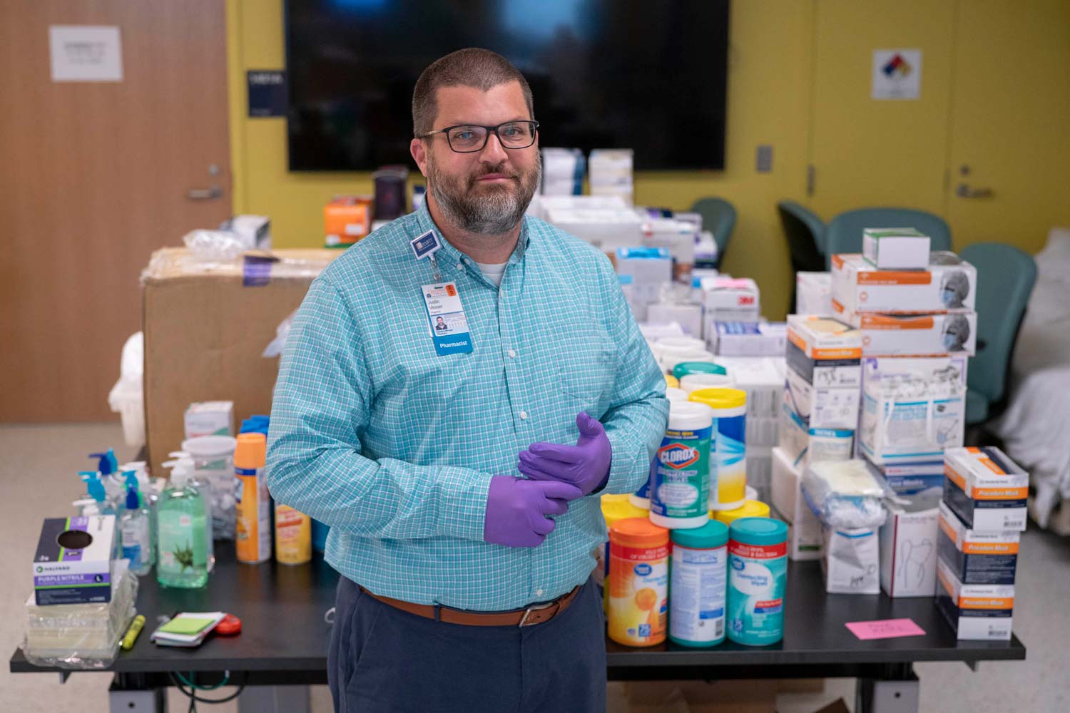 Man standing in front of a table with PPE and clorox wipes