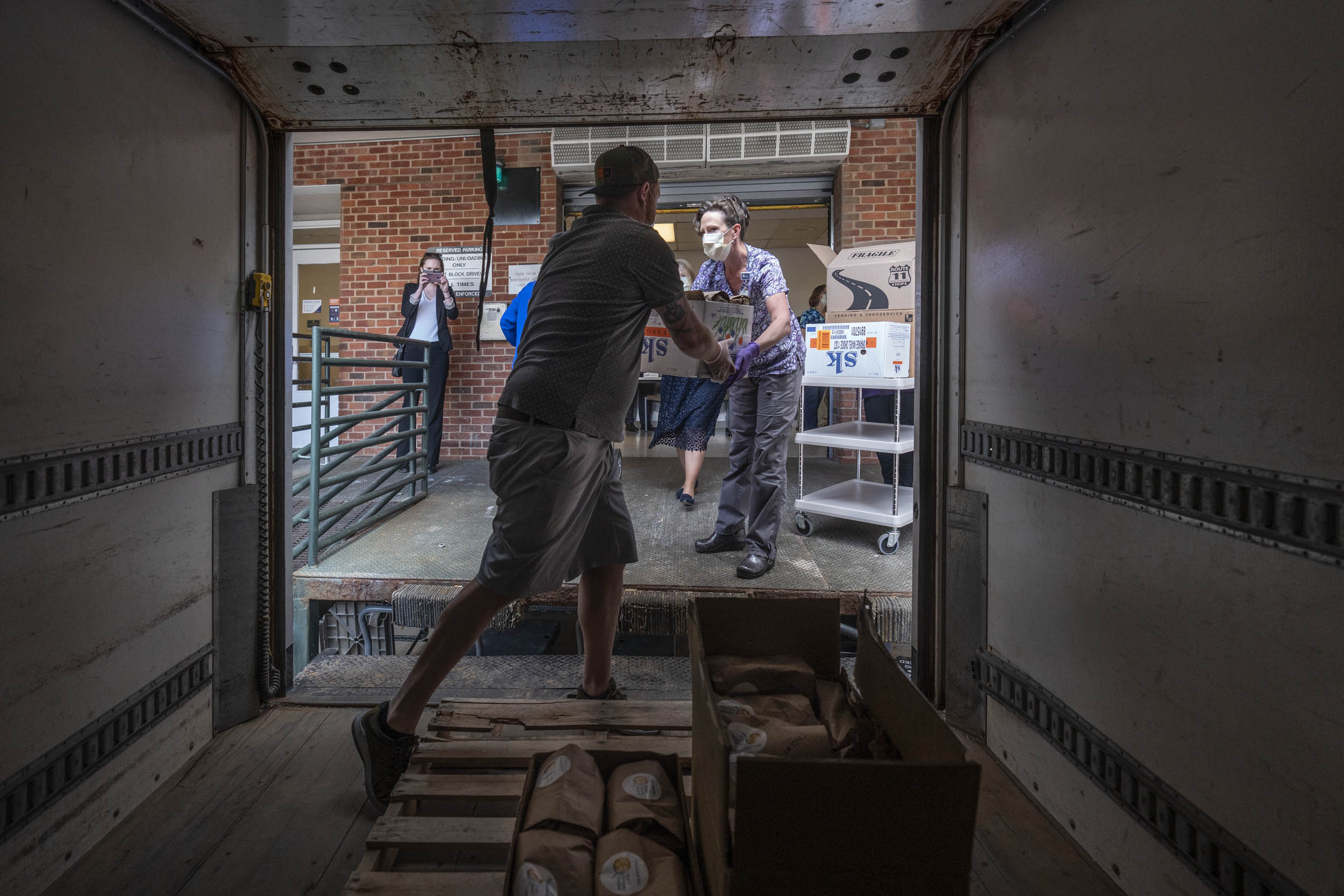 People loading a box truck with supplies