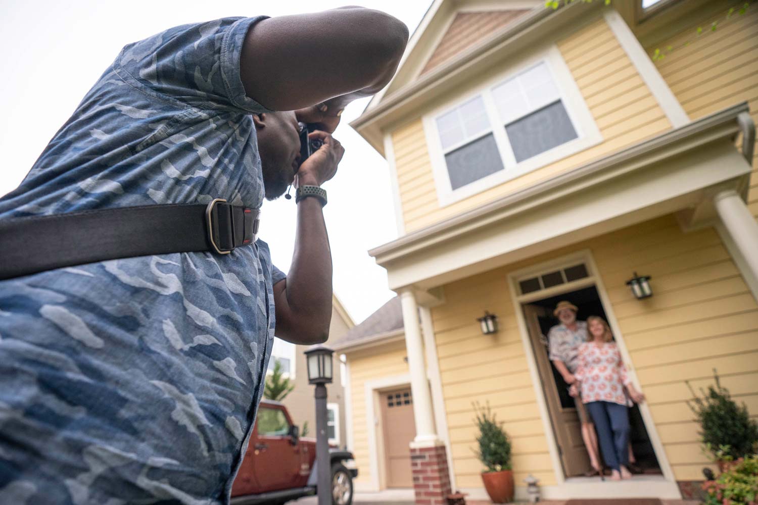 Person taking a picture of a husband and wife standing in their front doorway together