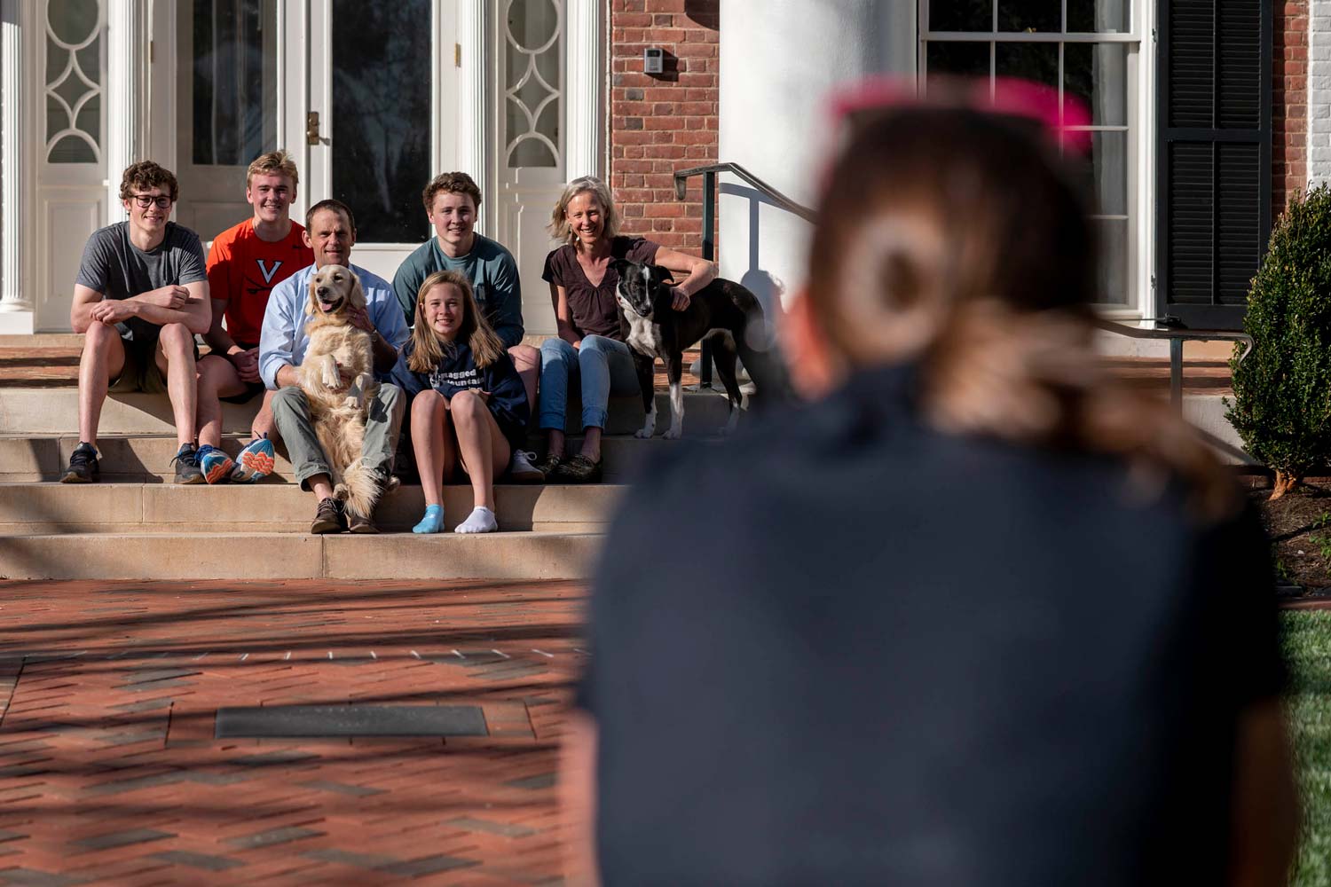 President Jim Ryan sits on the steps with his family and dogs as their picture is taken