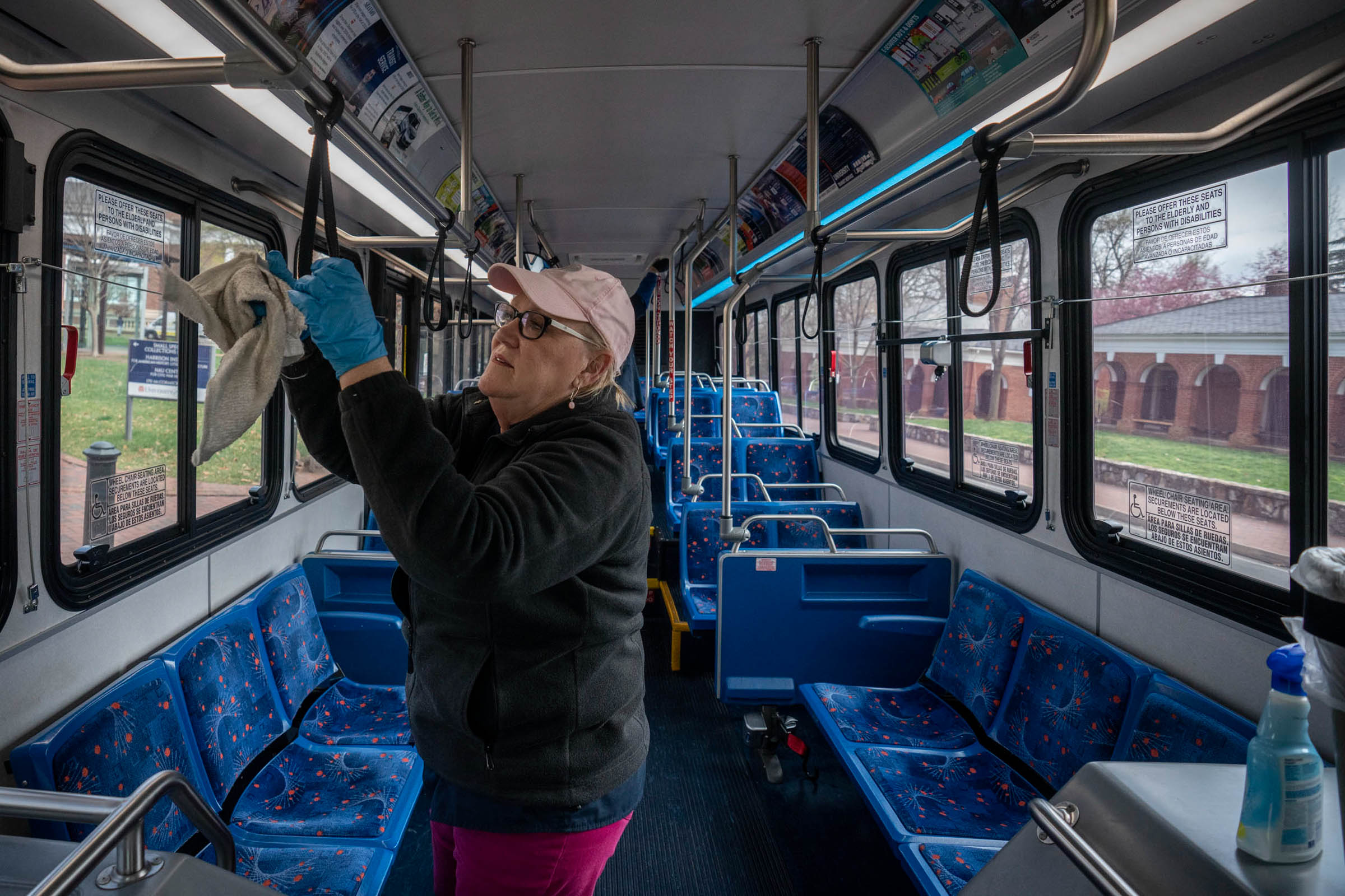 UVA transportation staff member wiping down handles on a bus with disinfectant