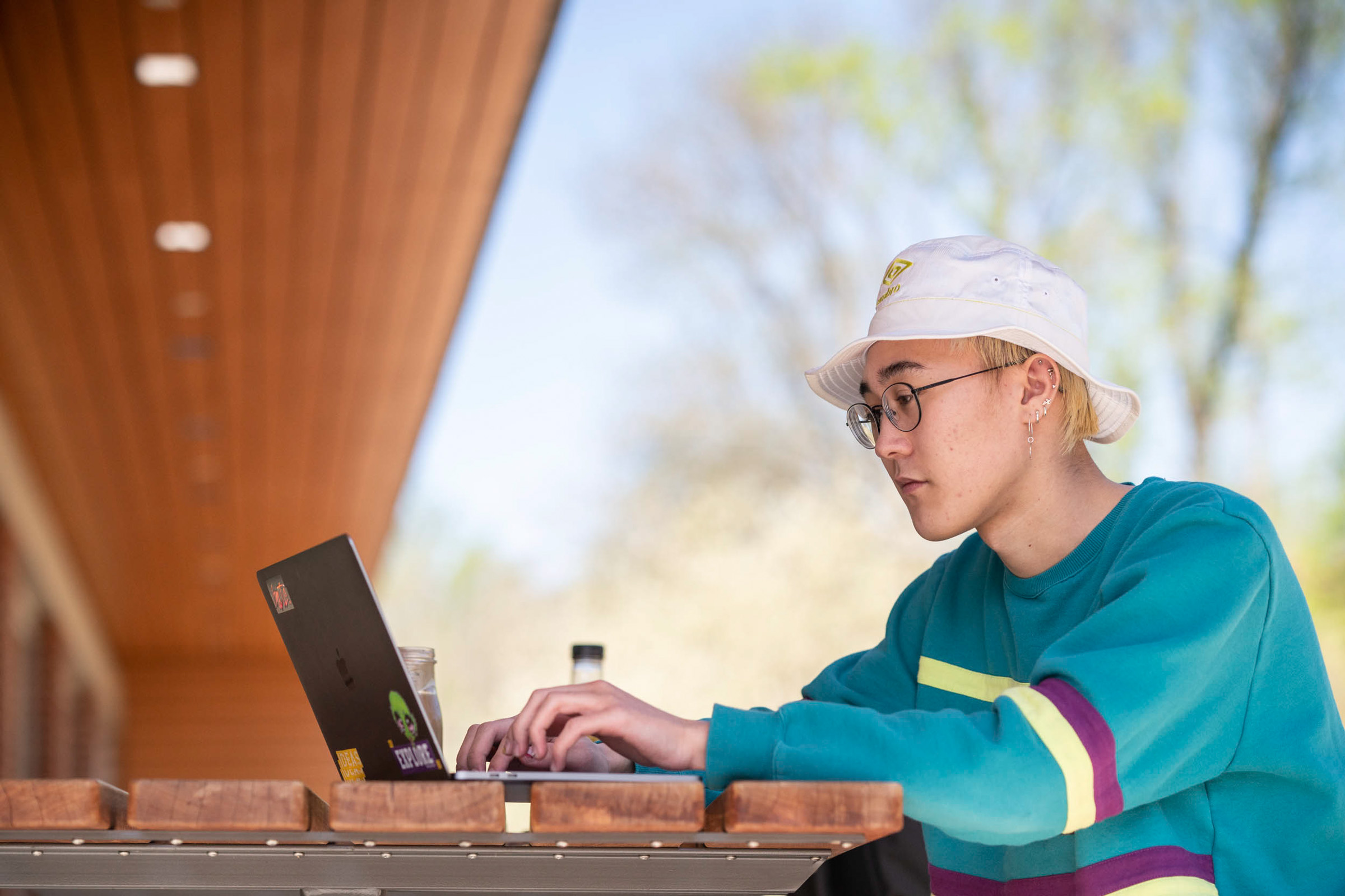 Student sitting at a picnic working on a laptop