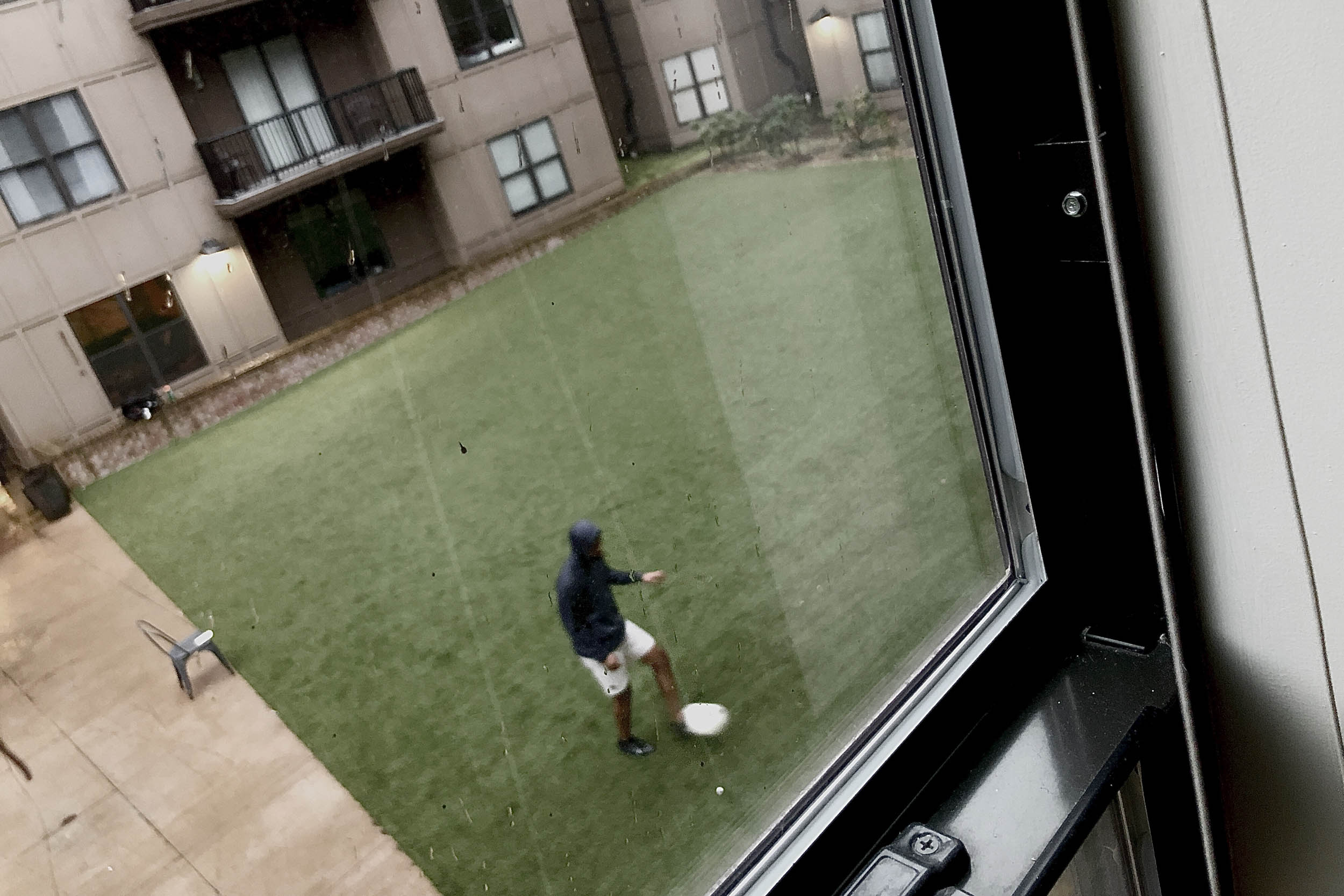Looking out of a window to a man below playing soccer
