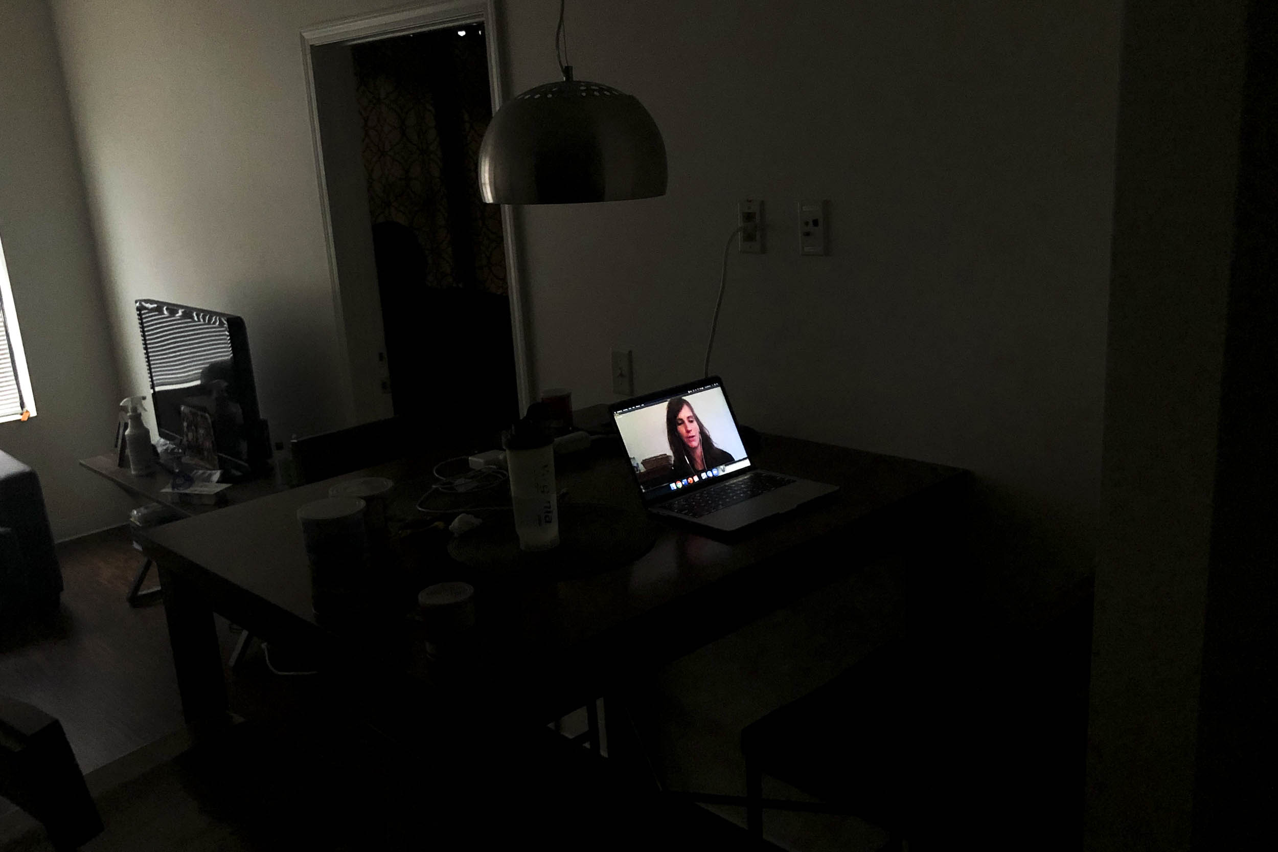 Dark room with a computer on with a womans face on the computer screen