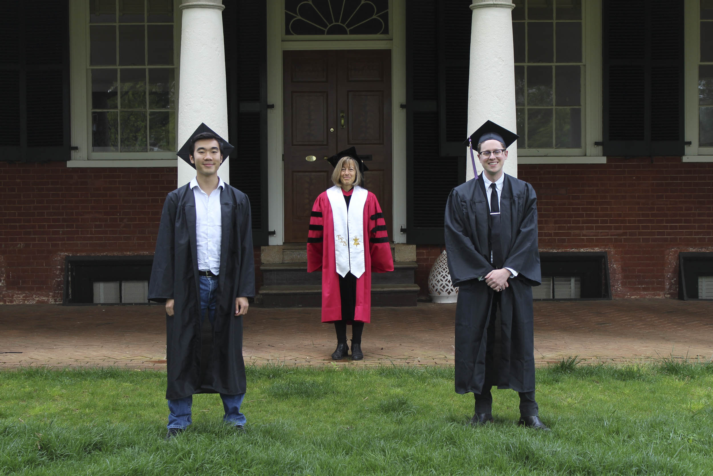Winston Tang stands socially distanced with two other people on the Lawn all dressed in their graduation hat and gowns