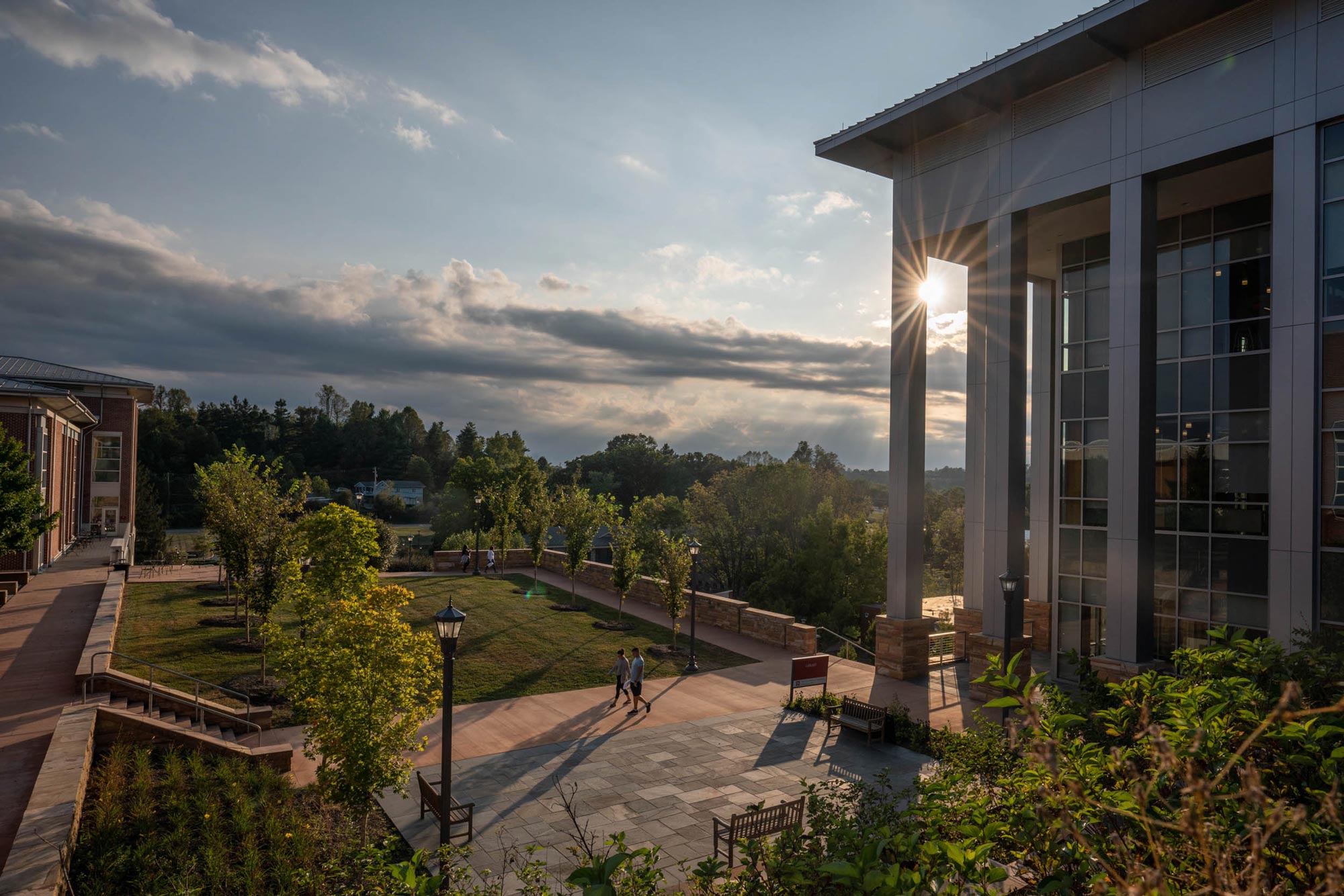 View from a building on grounds with the sun going down with dark grey clouds coming in