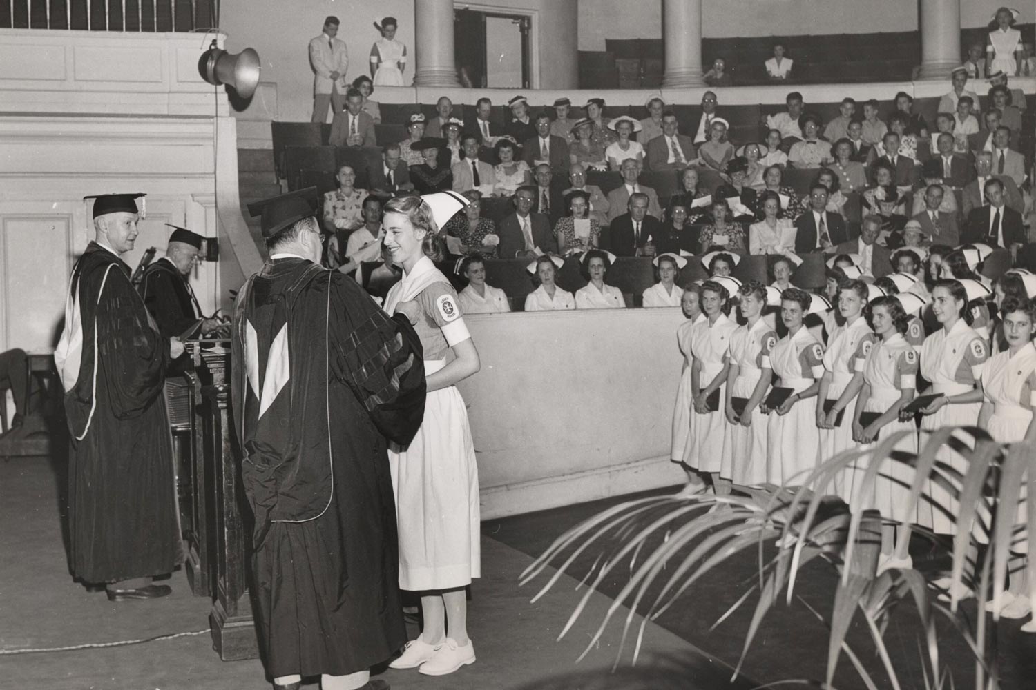 This nursing graduation ceremony in 1947 in black and white with nurses standing and one nurse on stage