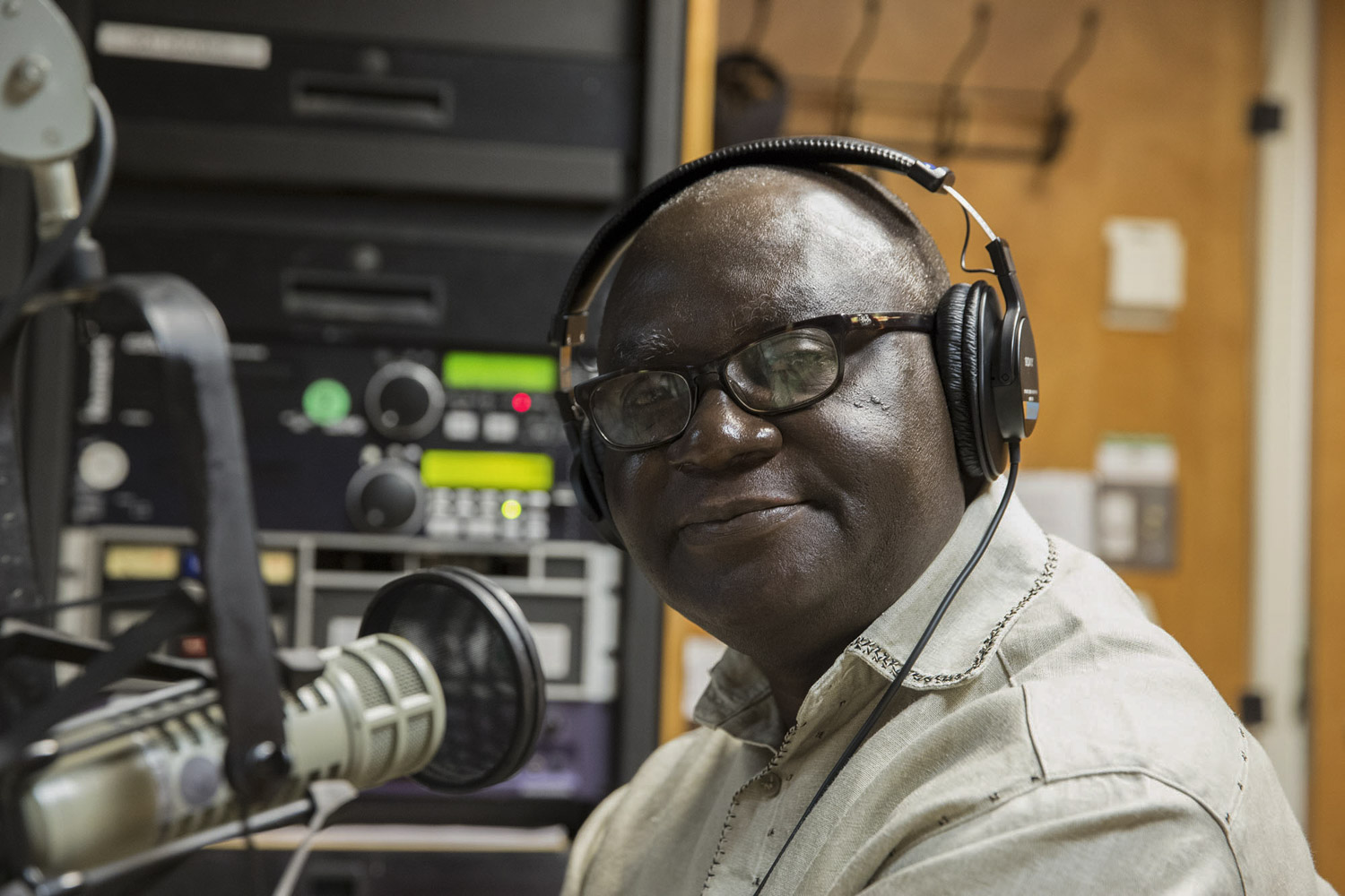 Kwesi Ghartey-Tagoe smiling at the camera in front of a microphone wearing headphones