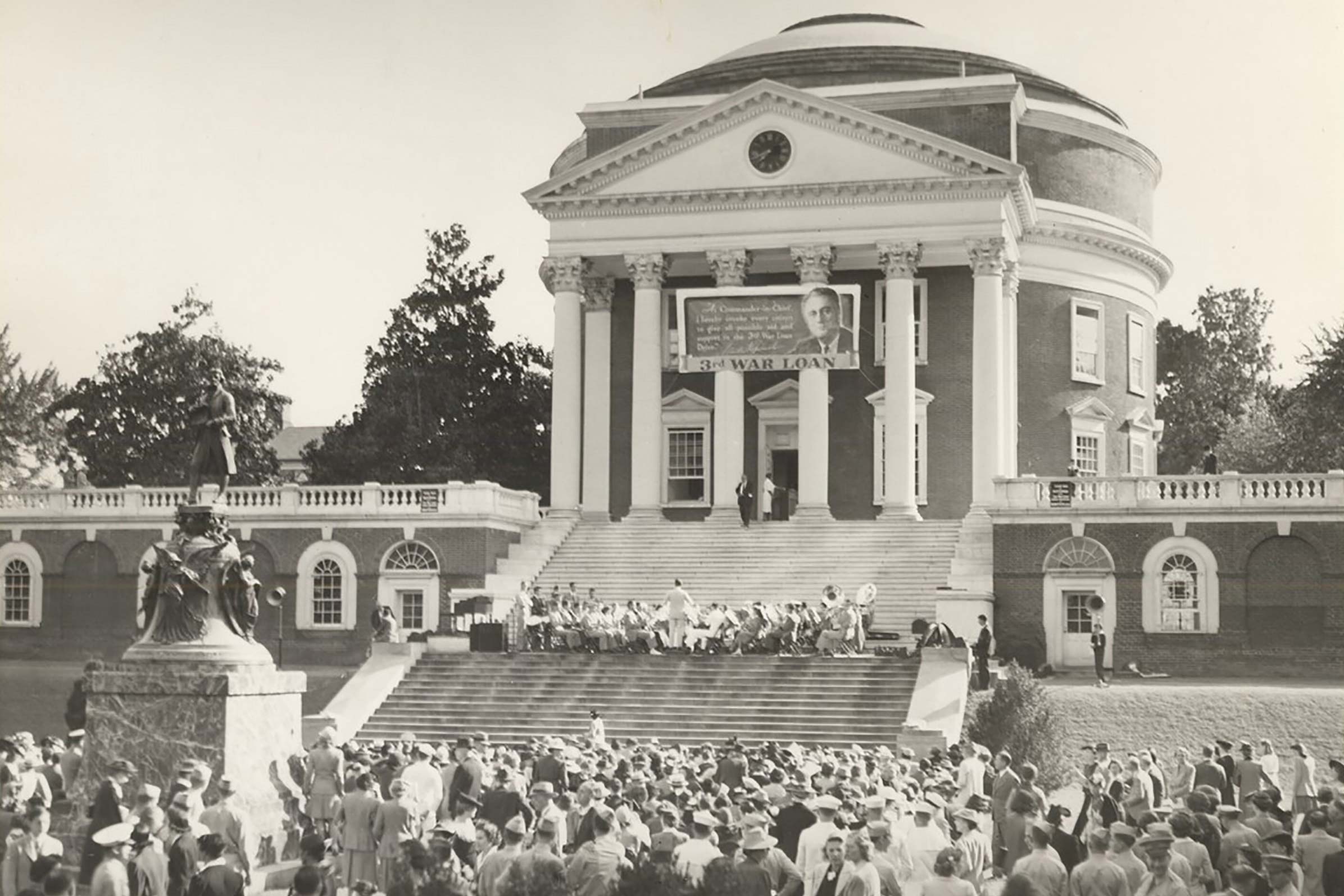 Black and white photo of the Rotunda with a huge banner hanging from the columns in 1943