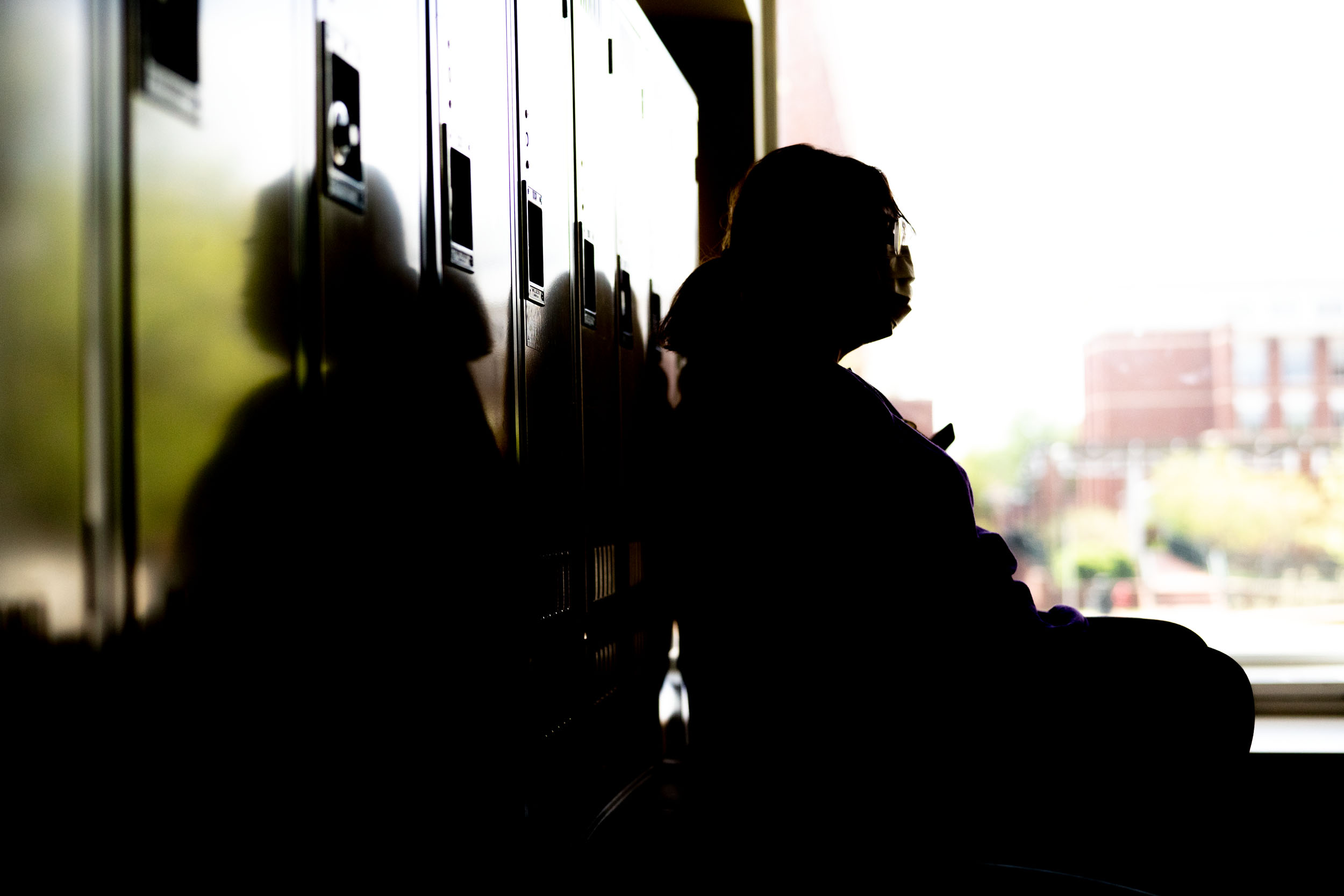 Person sitting on the floor resting on lockers and a next to a window