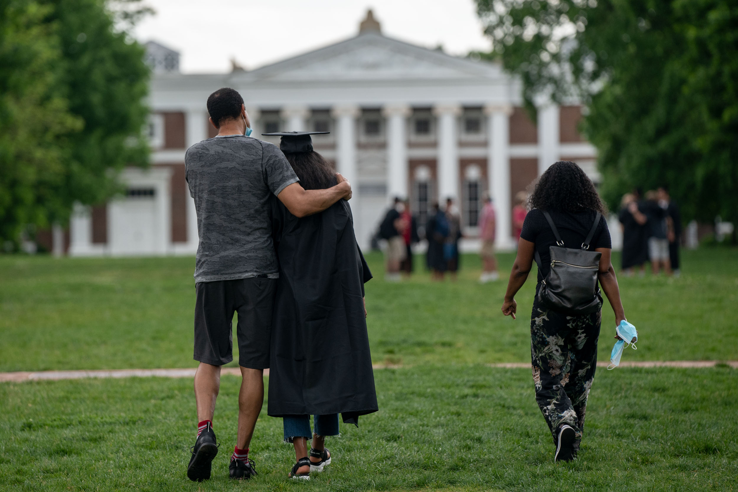 Graduate is hugged by a family member as they walk on grounds together