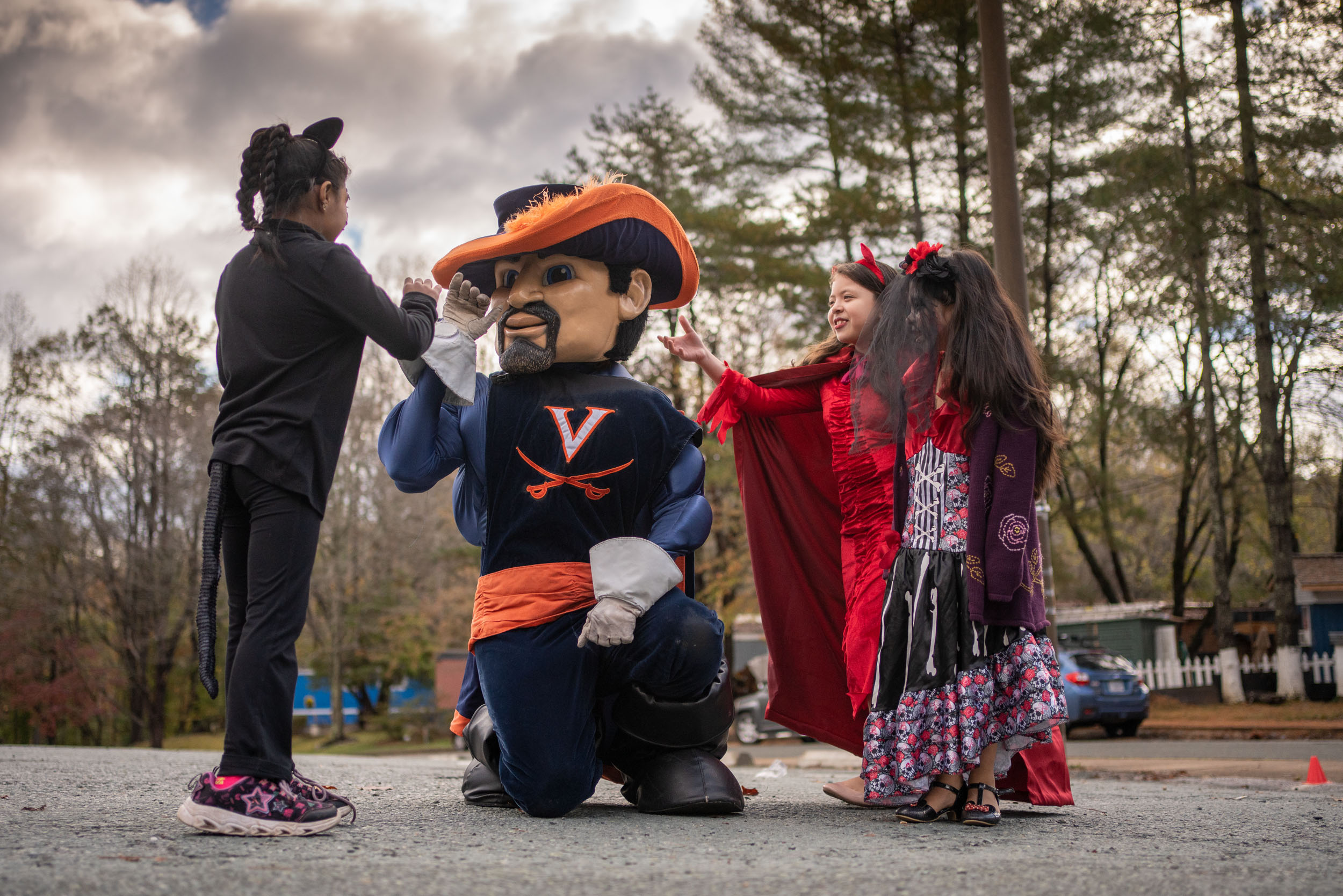 Cav Man kneeling to interact with three little girls dressed up for halloween