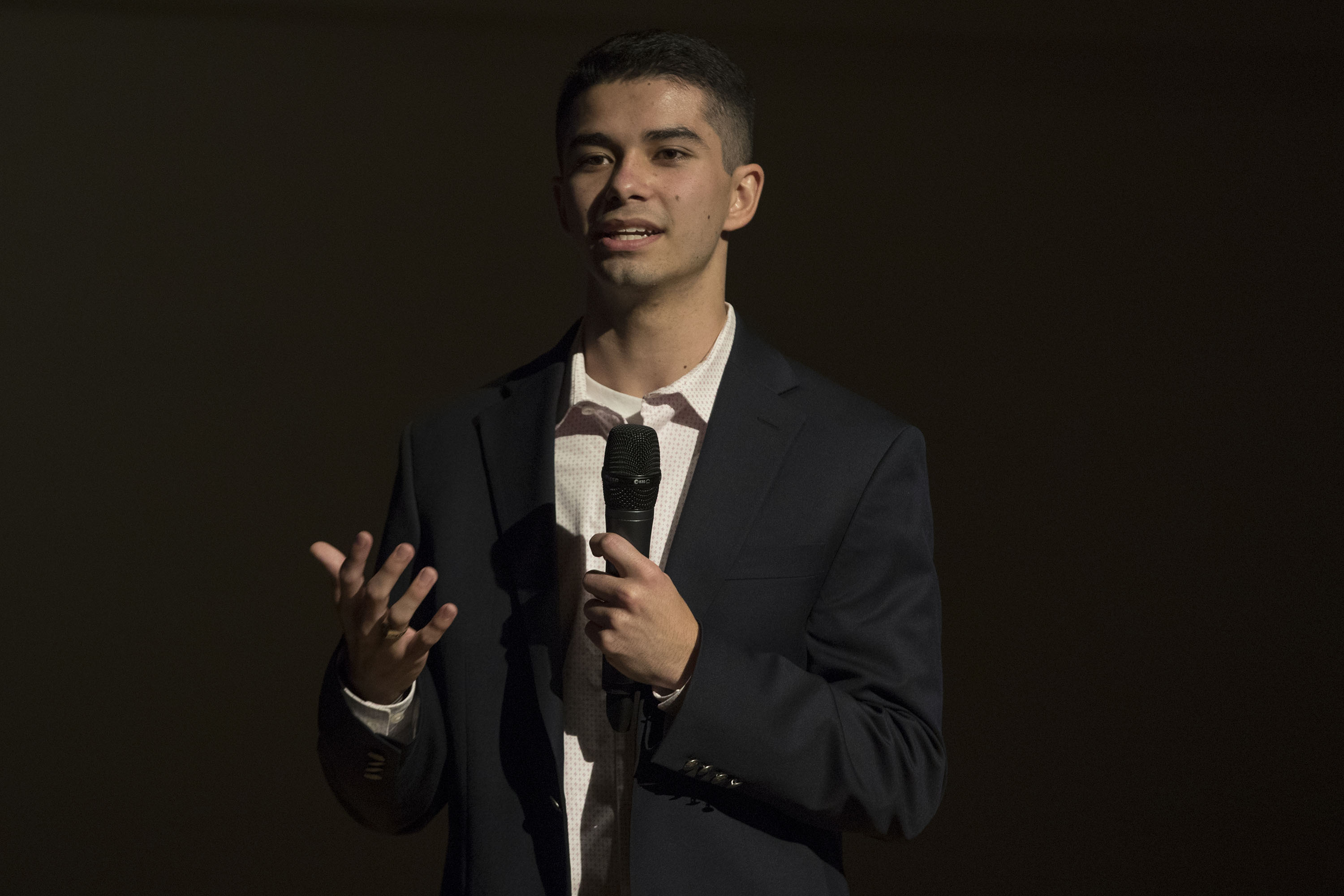 Zachary Phillips stands on stage talking into a microphone