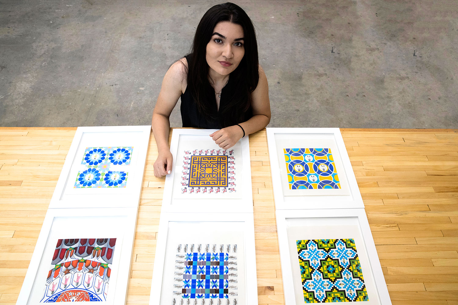 Feraidon with the paintings in her “Hide and Seek” series. She used photos of Afghan women to create some of the patterns seen here, including the borders of the two paintings in the middle row and the central figures of paintings in the first and third rows. (Photo by Dan Addison, University Communications)