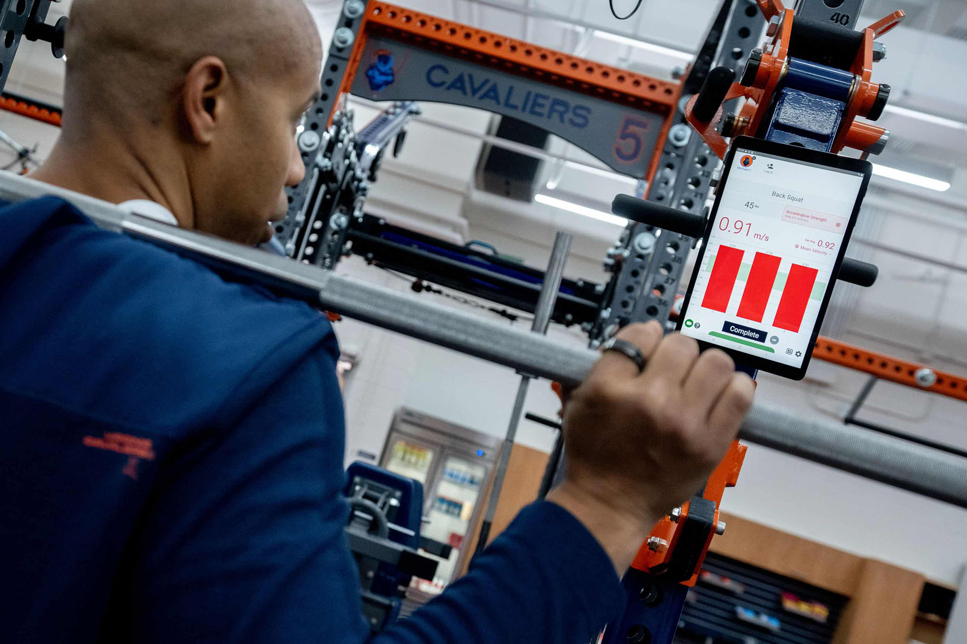 Person in a squat rack looking at the data collected