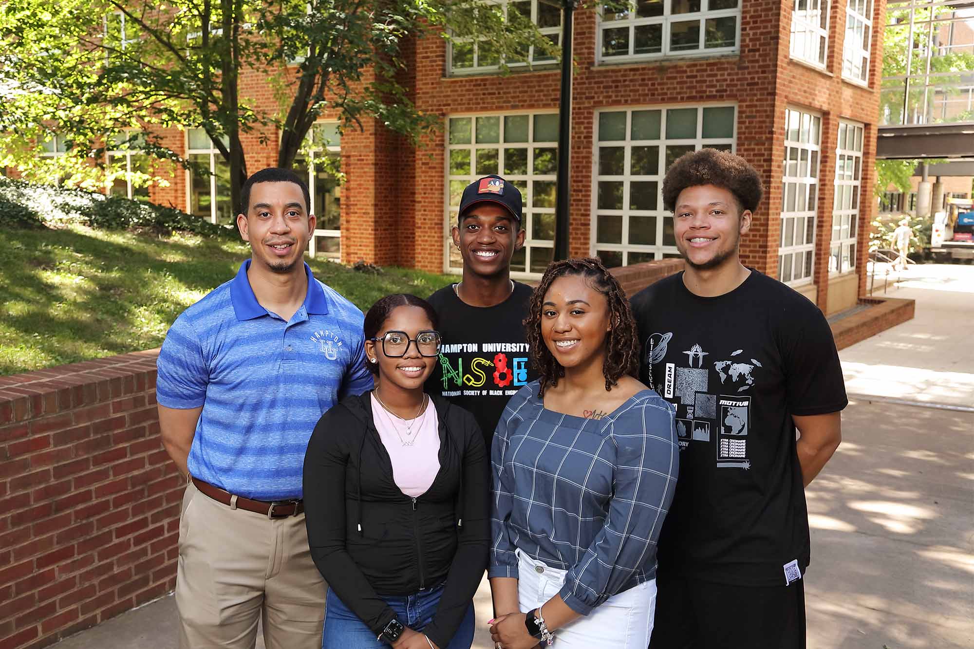 Hampton University students and professor stand on Grounds at UVA, smiling at the camera.