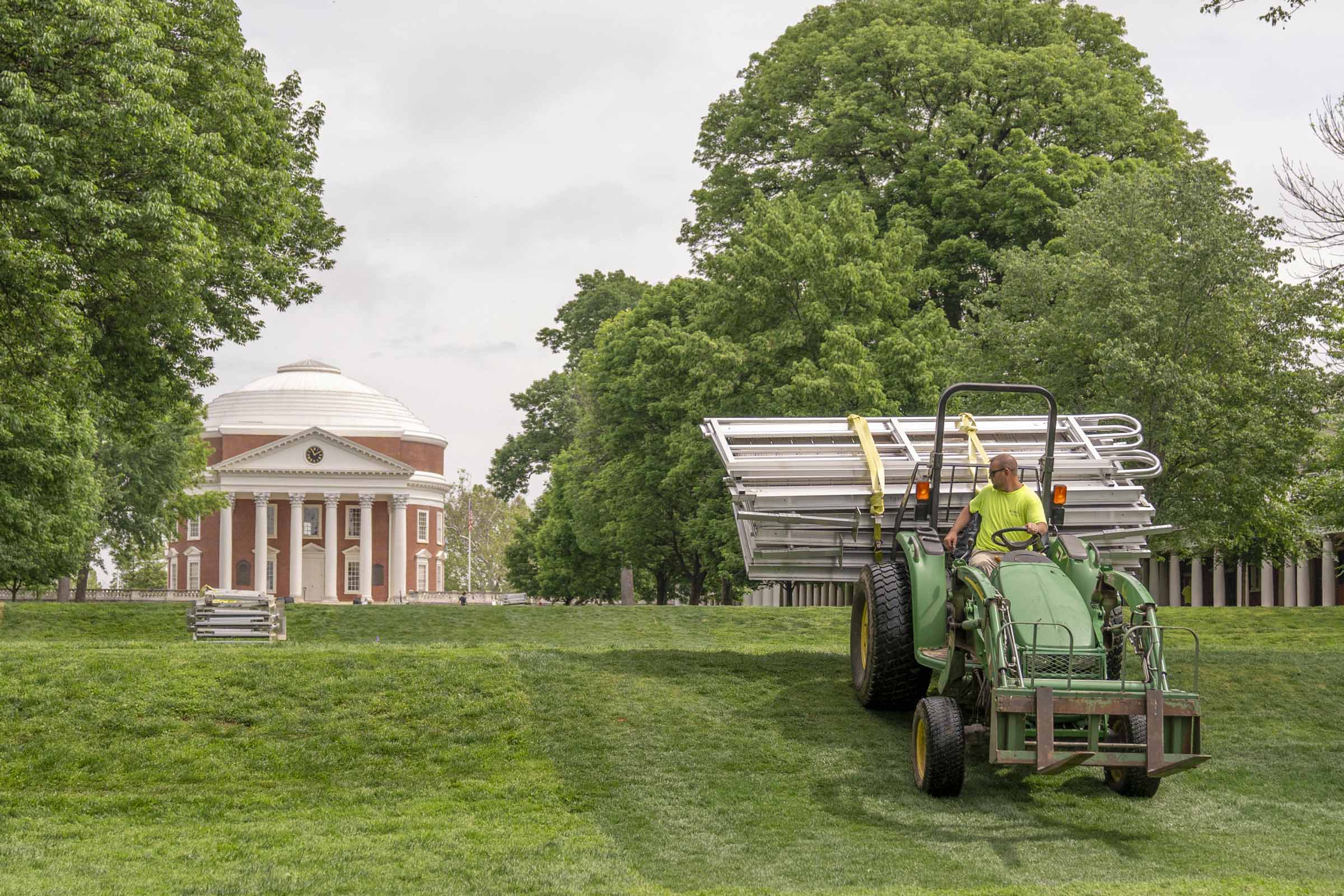 Tractor holds stacked ramps as it moves up a small hill toward the Rotunda