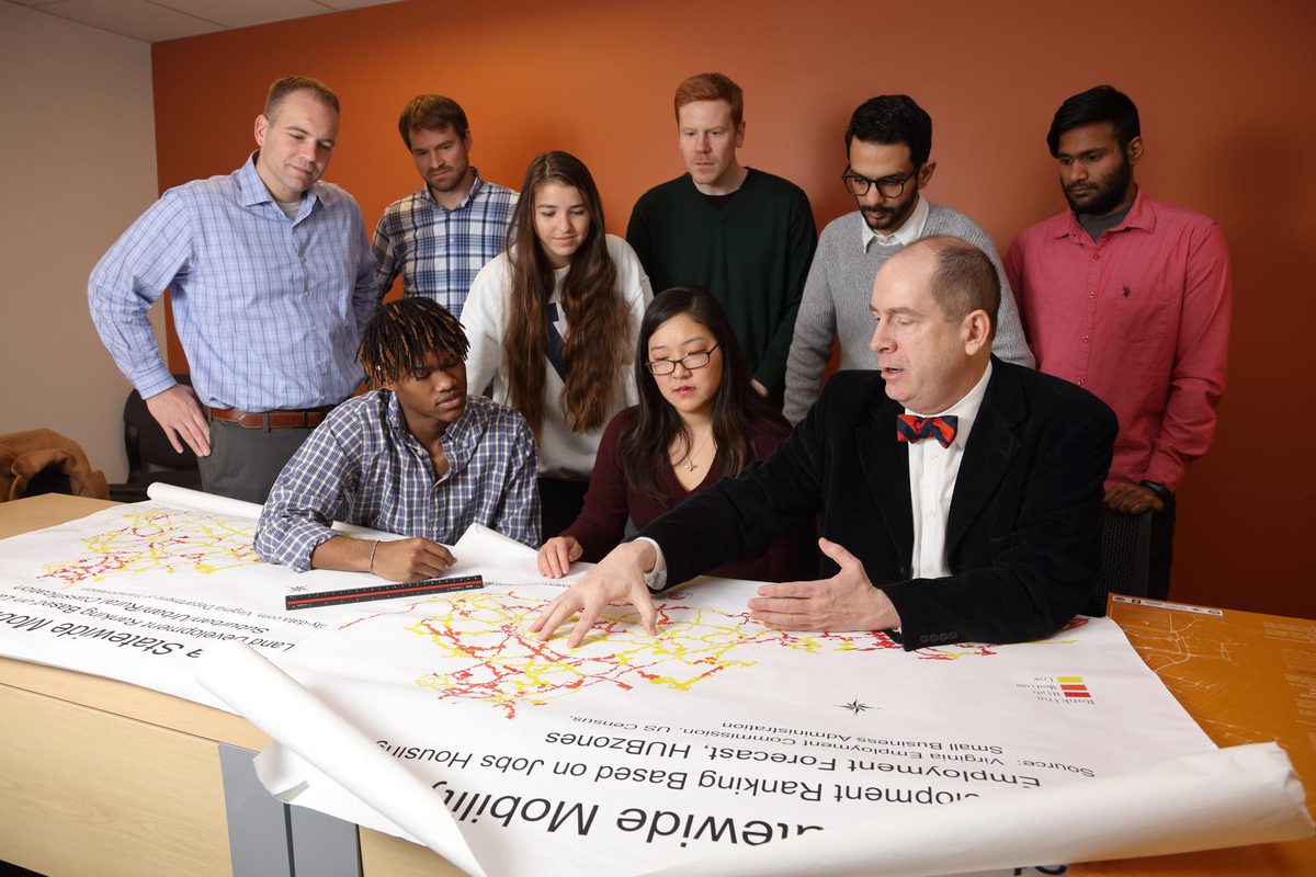 James H. Lambert, front right, talks with student researchers at a table