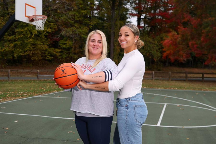 Jessica Thomas-Johnson and Kymora Johnson together on a basketball court showing their matching tattoos